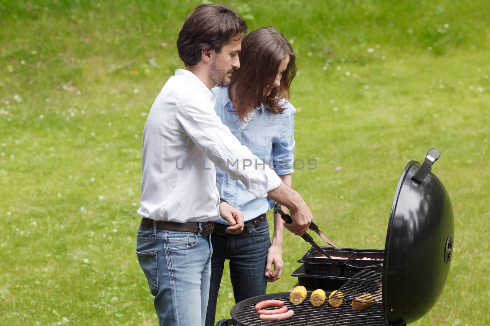 Happy couple cooking food on barbecue