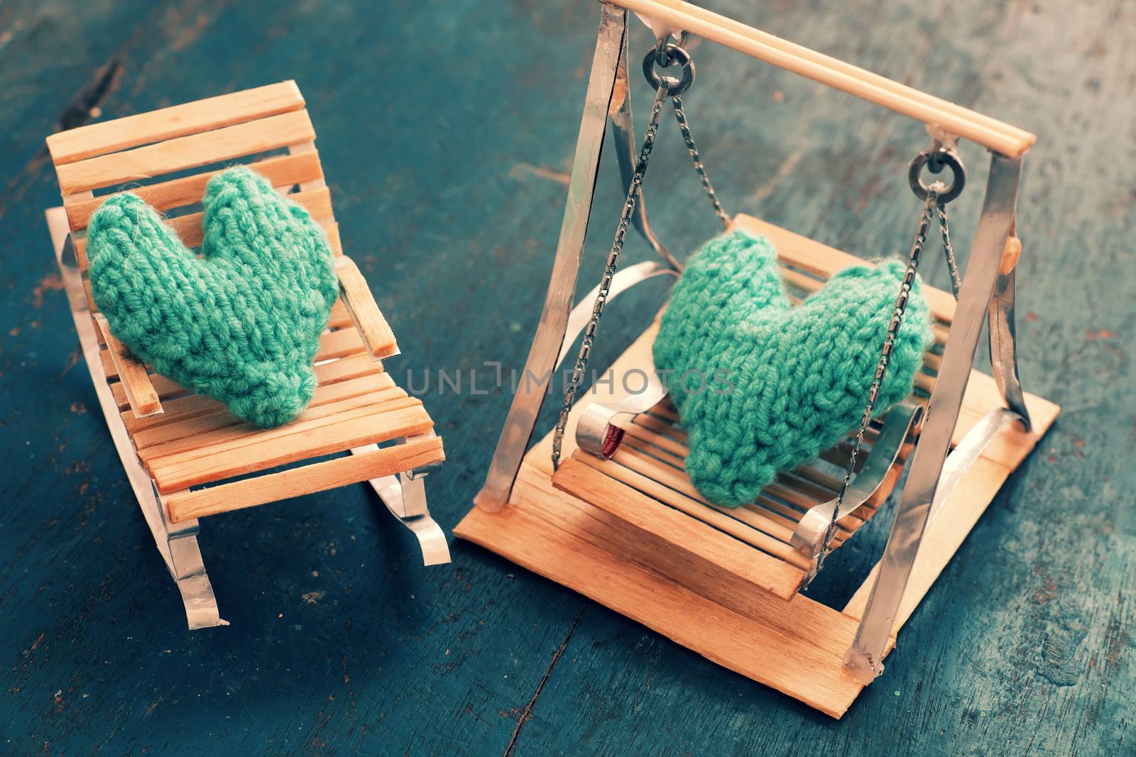 Two hearts be together, illustration for couple in love, take care and loving, green heart on handmade mini furniture as chair, swing, bed on wood background