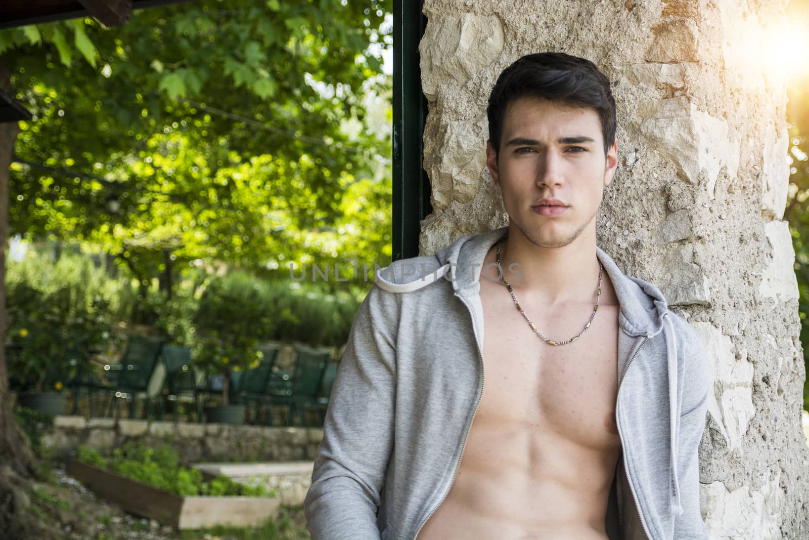 Handsome young man leaning against tree, by artofphoto