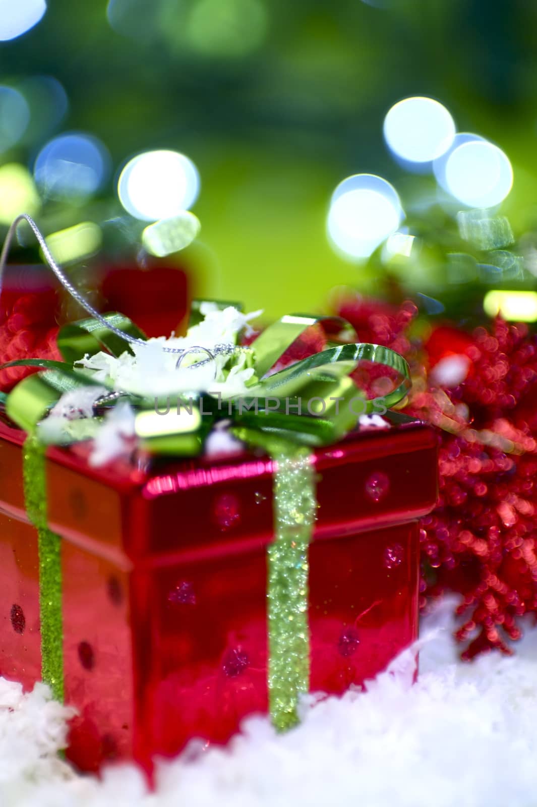Presents Sharing Holiday Photo Theme. Small Red Christmas Boxes with Green Bows. Cool Green Bokeh and Fake Snow.