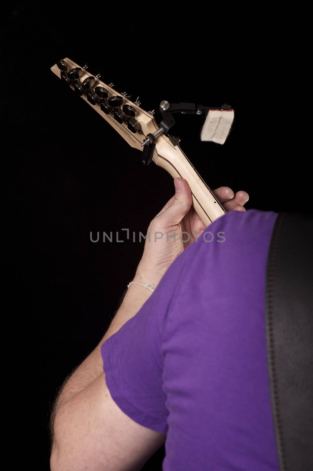 Guitar Play. Vertical Photo of the Guitar Player. His Shoulder, Hand and the Guitar. Solid Black Background.