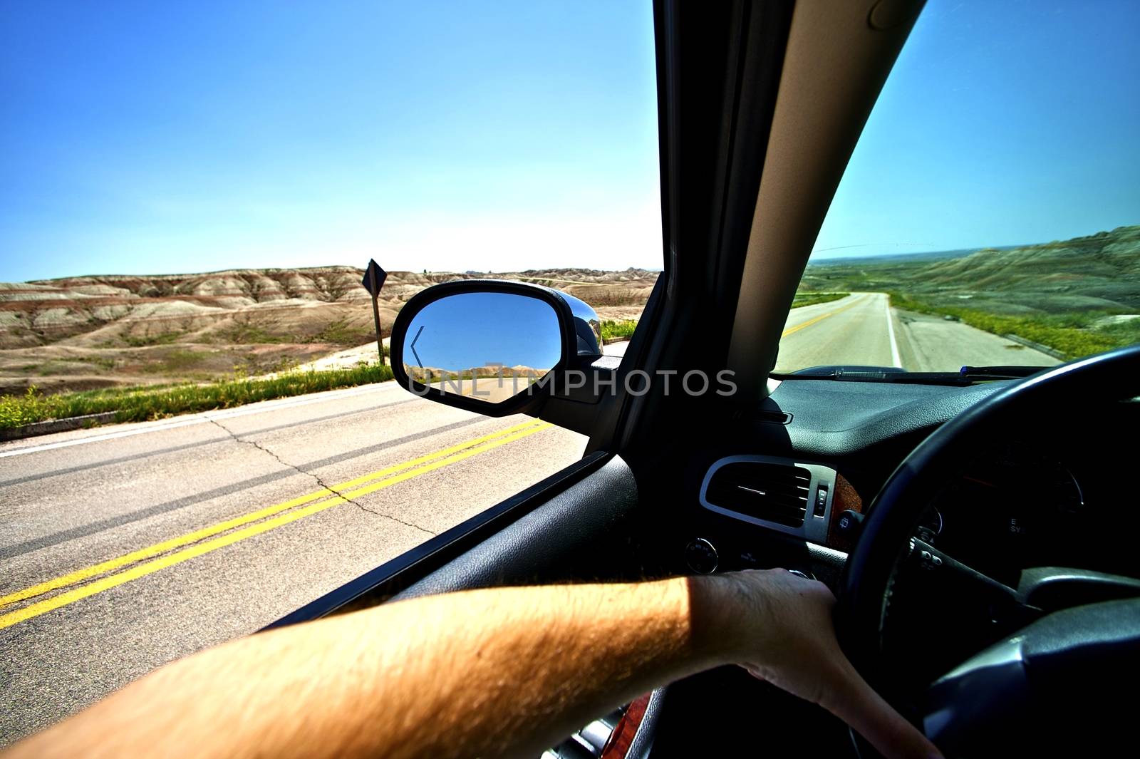 Driving Thru Summer. Summer Ride in Badlands. Wide Angle Photo Taken From Inside the Car. Male Hand on a Wheel. Transportation Photo Collection.