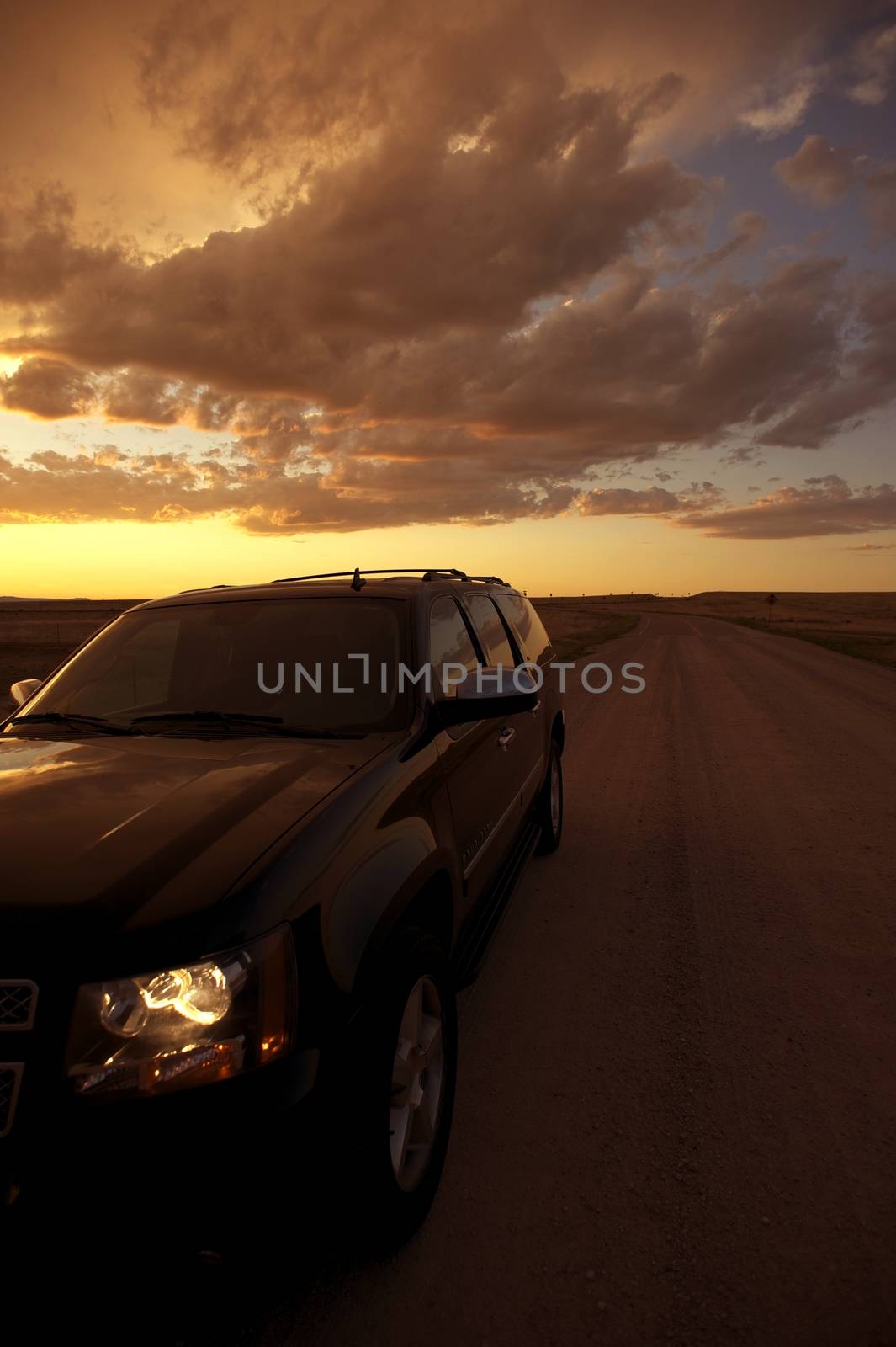 Riding Thru Great American Plains. Black SUV on the Country Road. Vertical Photo at Sunset. Traveling Photo Collection.