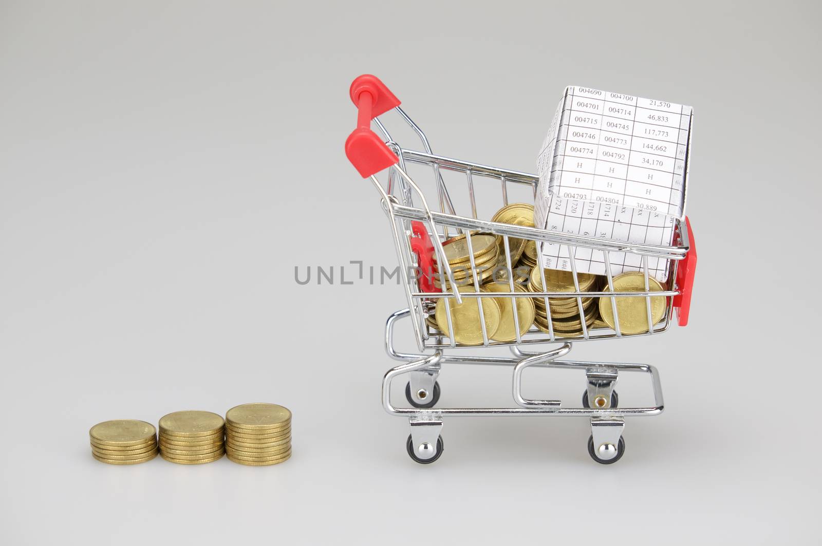 House in shopping cart with gold coins and step pile of gold coins place on white background.