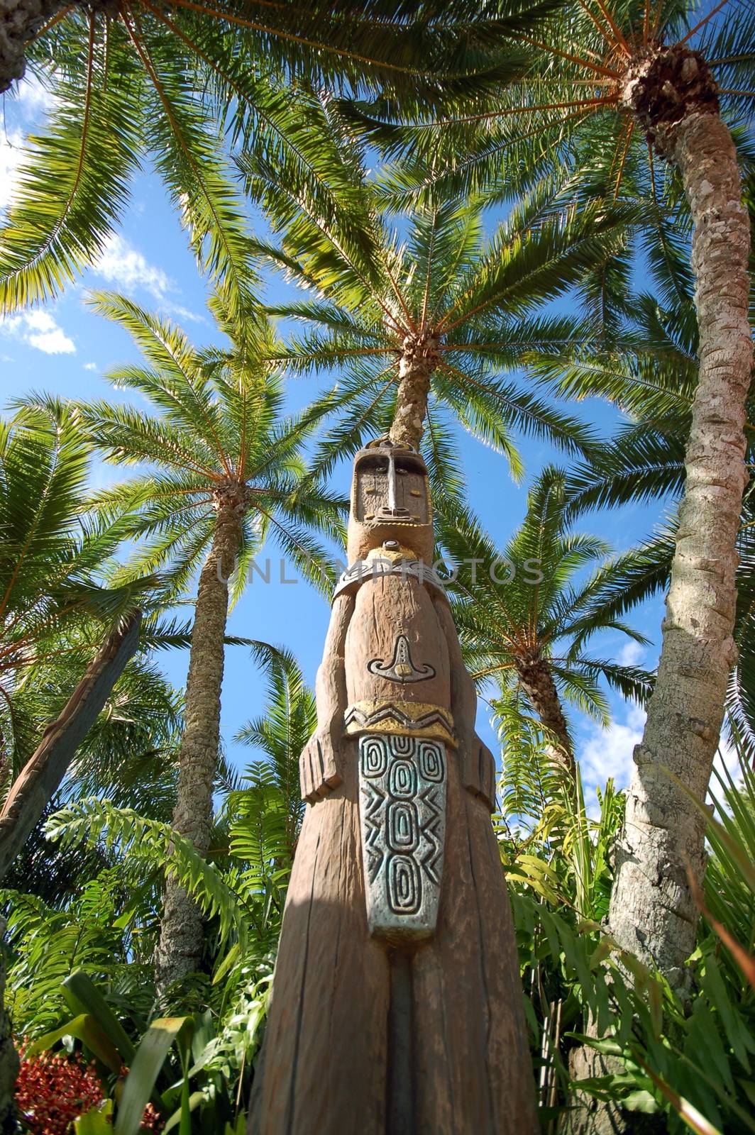 African Wood Sculpture Between Palm Trees. African Theme
