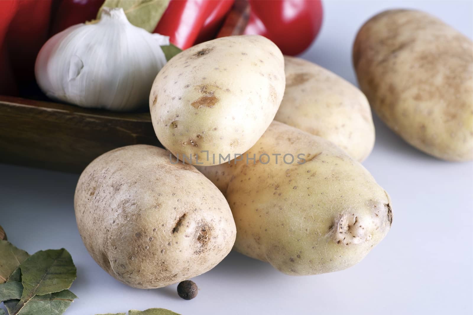 Organic Raw Potatoes on White Table with Some Other Vegetables in Background. Potatoes Horizontal Photo.