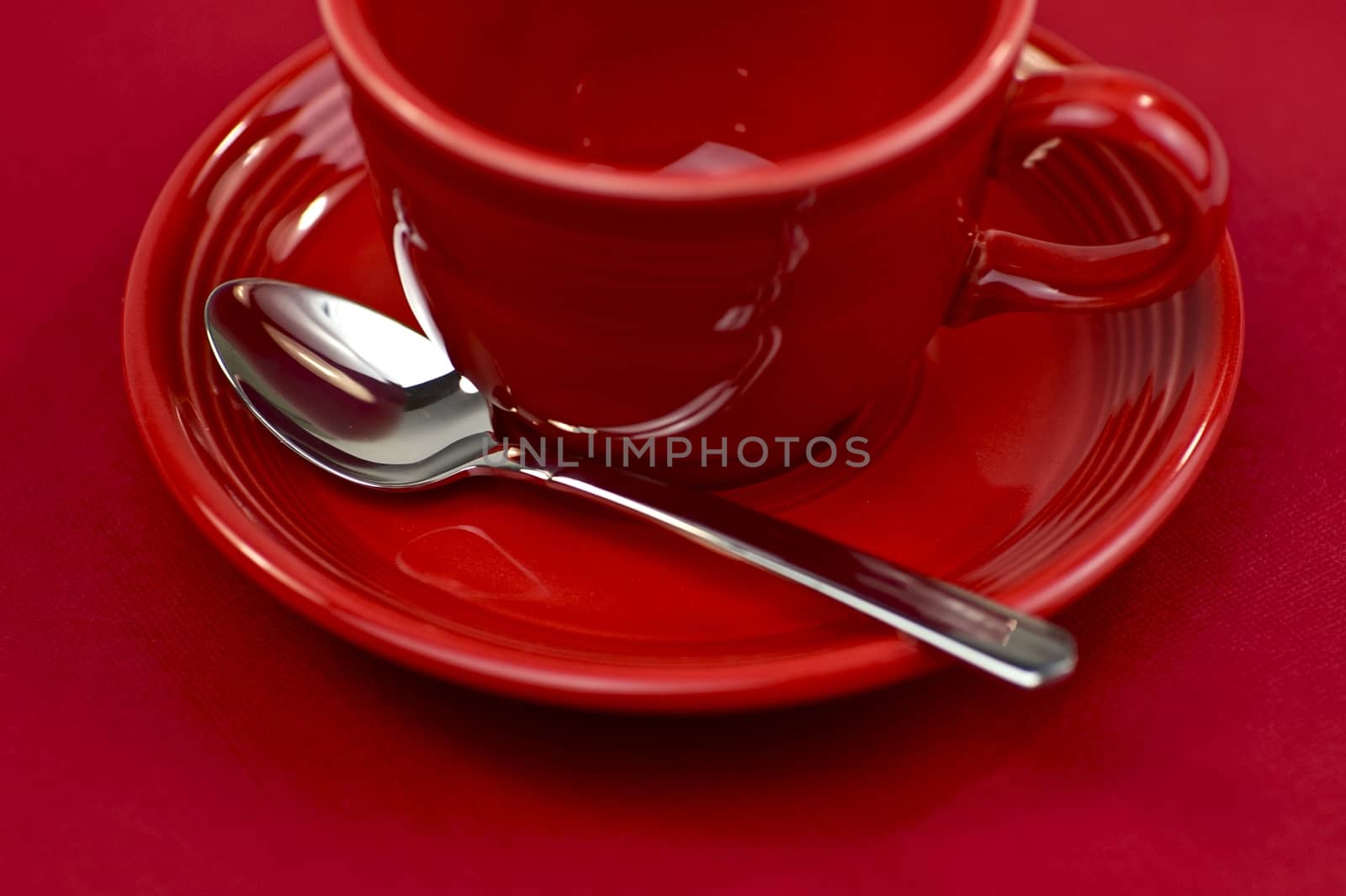 Red Empty Tea Cup, Silver Spoon and Red Background.