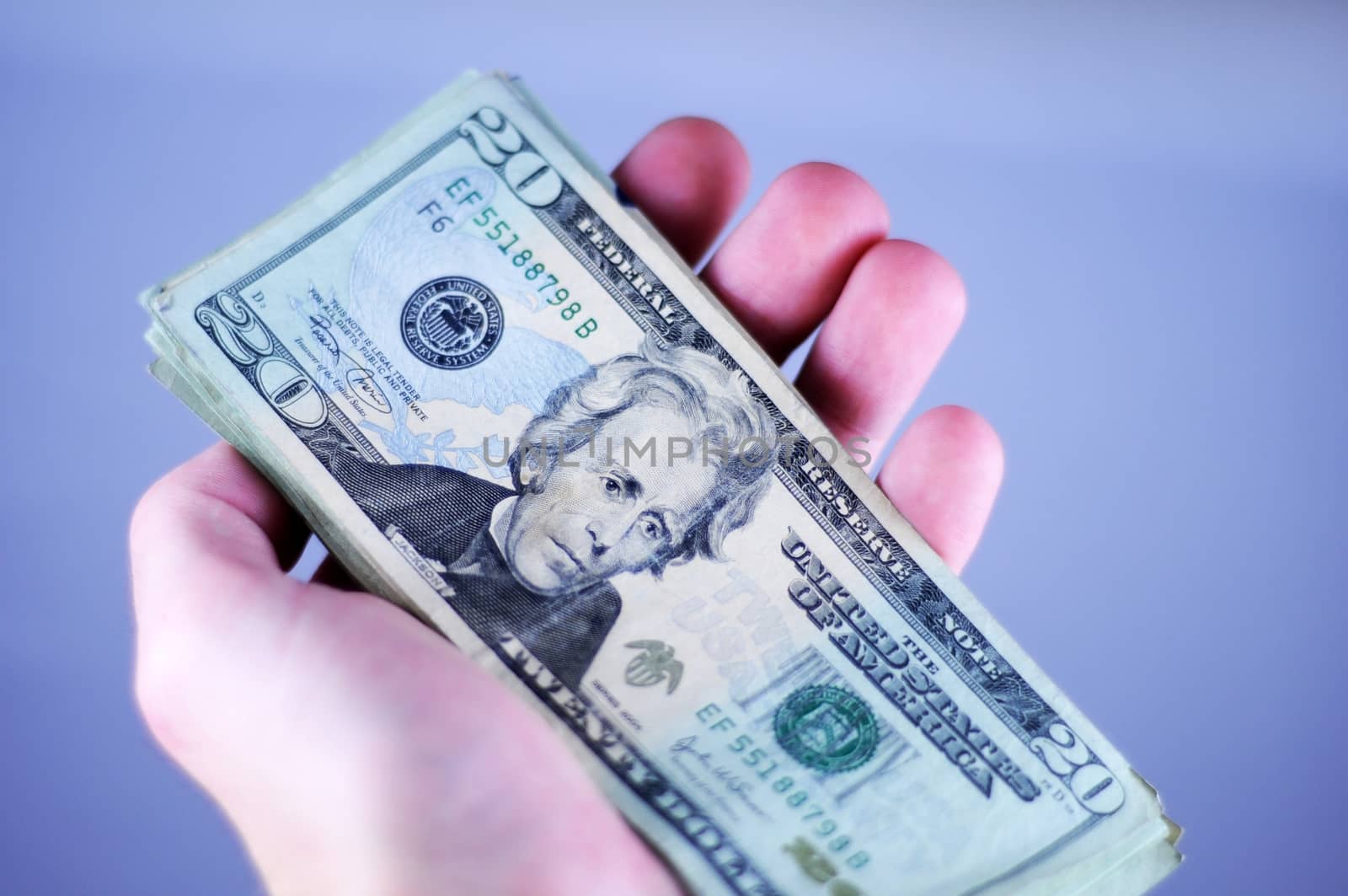 Dollar Bills. Twenty Dollars Bills in (Male) Hand. Blue Background