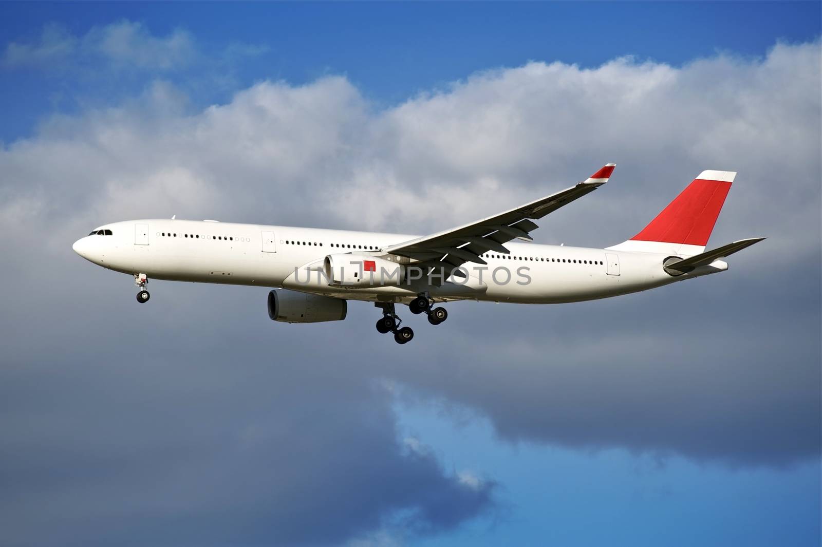 Airliner Arrival. Large Commercial Airliner / Aircraft with Lending Gear Prepared for Landing. White Aircraft with Red Element. Party Cloudy Sky. Transportation Photo Collection.