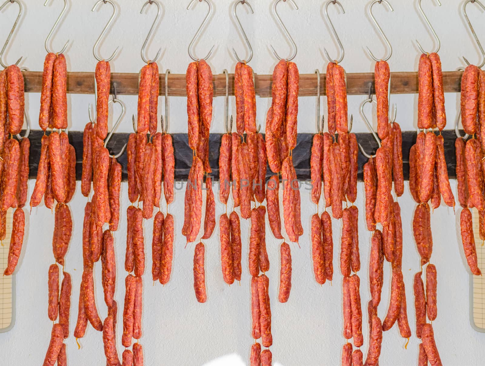 Various smoked sausage or salami in a butcher shop on meat hook.