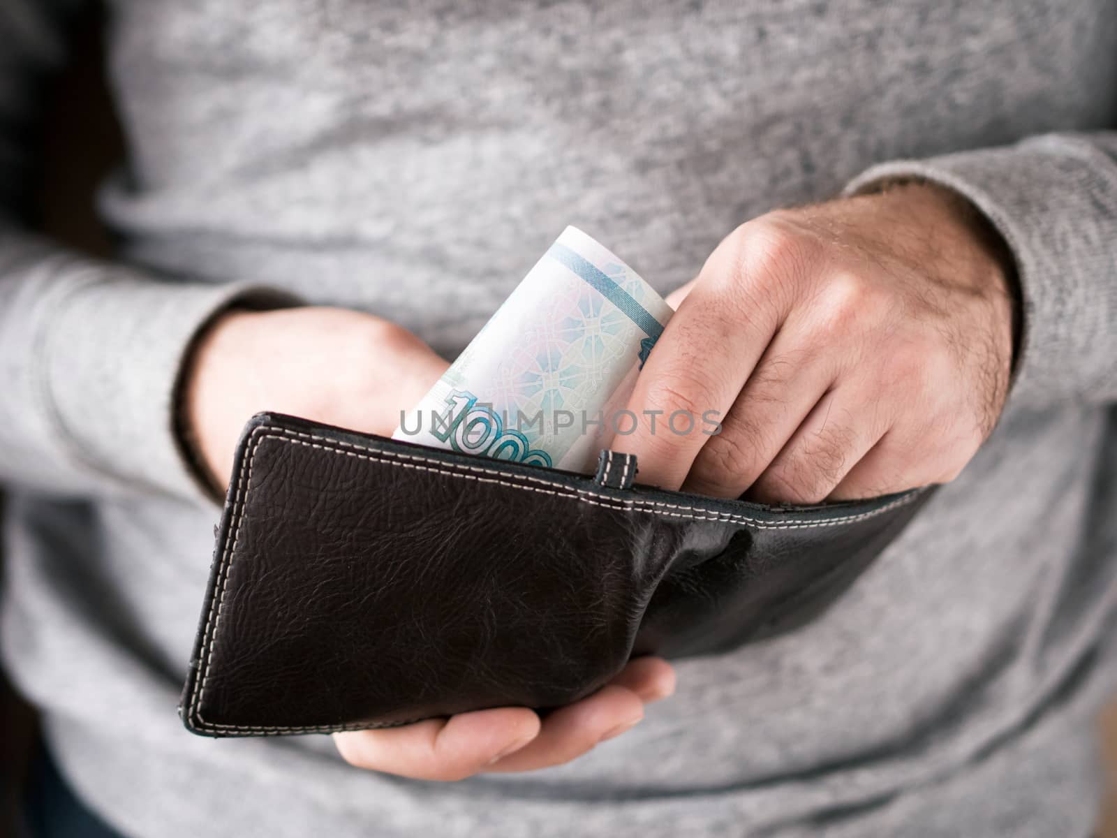 Hands take out russian rubles from wallet. Closeup on a man's hands as he is getting a banknote out of his wallet