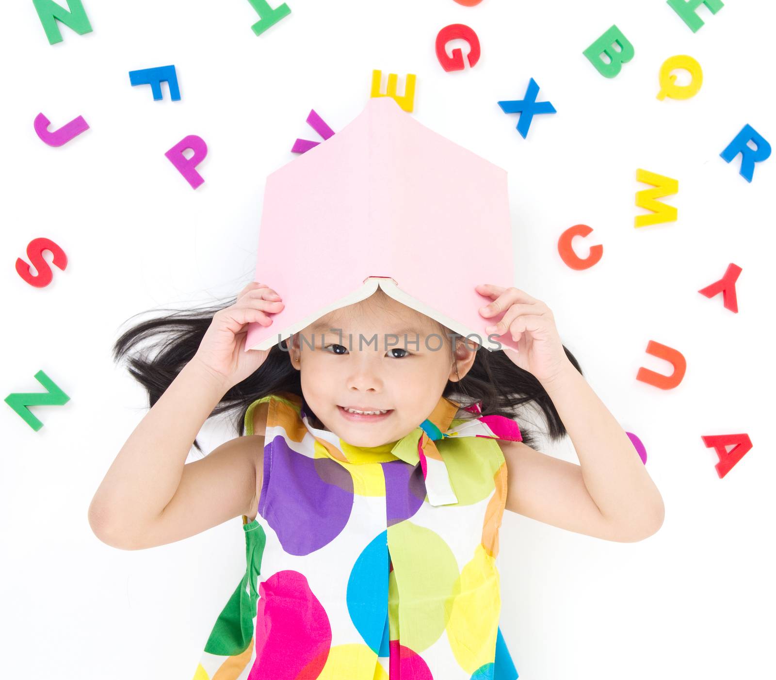 Lovely asian girl lying on the floor, holding a book, playing with Alphabets