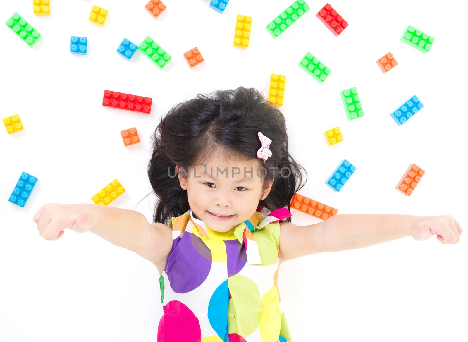 Lovely asian girl lying on the floor, playing with colorful blocks