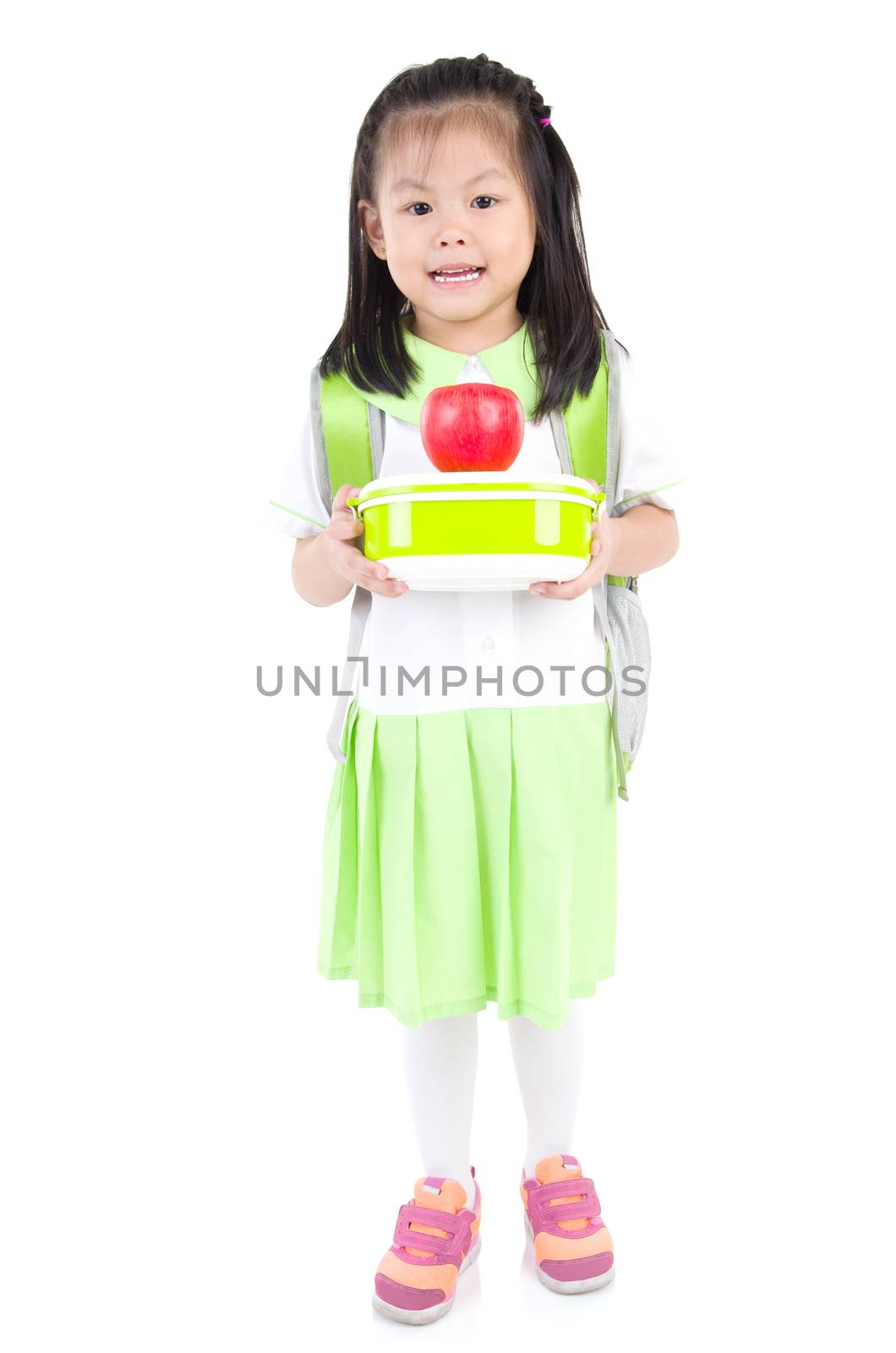 Asian primary school girl holding lunch box and apple. Healthy eating concept for schoolchild.