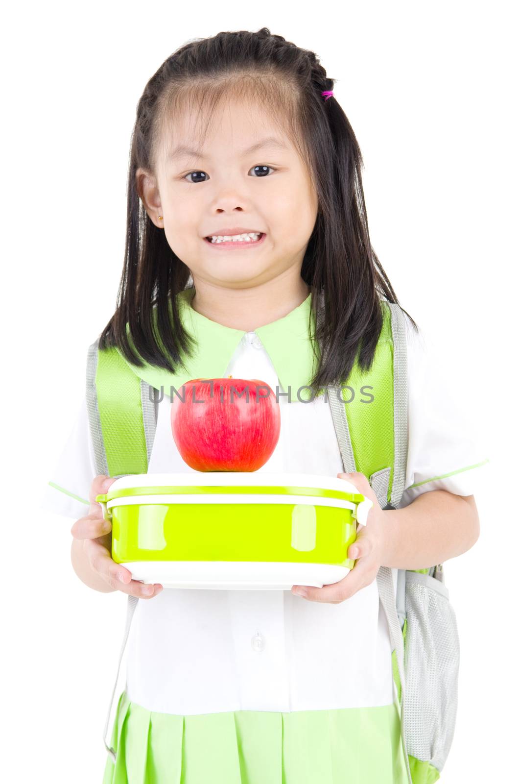 Asian primary school girl holding lunch box and apple. Healthy eating concept for schoolchild.