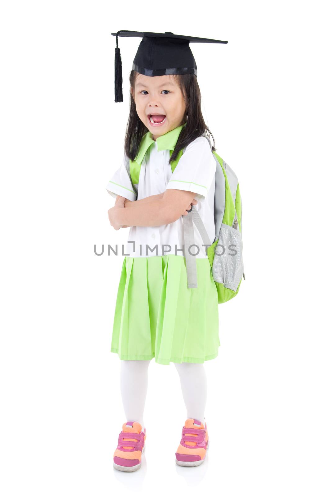 Asian primary student carried school bag and wearing mortarboard, isolated on white background