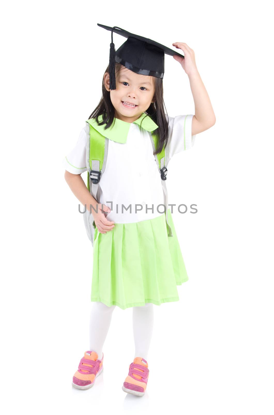 Asian primary student carried school bag and wearing mortarboard, isolated on white background