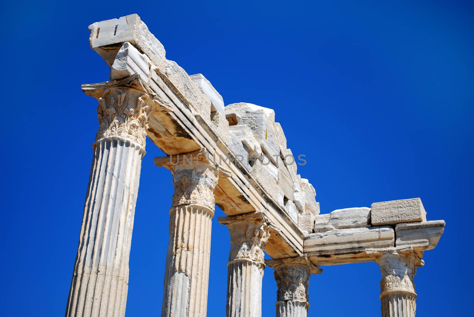 Ruined Columns of Ancient Greek Temple on Blue Sky Background