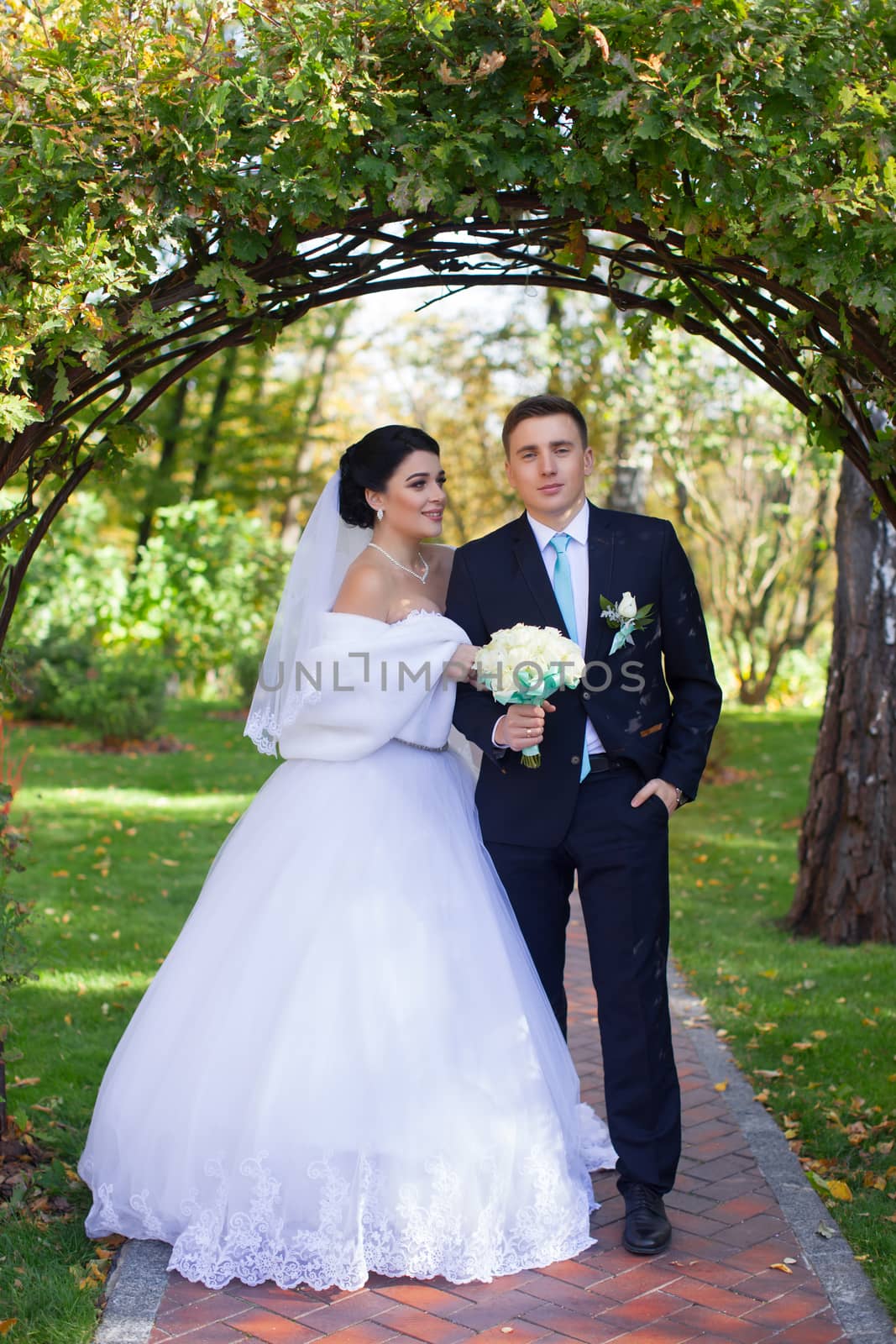 The bride tenderly embraced the groom standing under the green arch