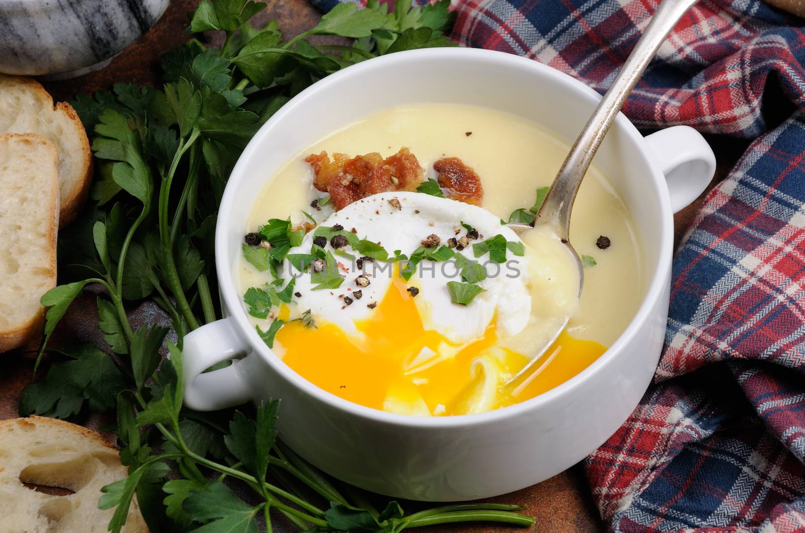 Garlic potato cream soup with bacon and poached eggs, herbs, spices