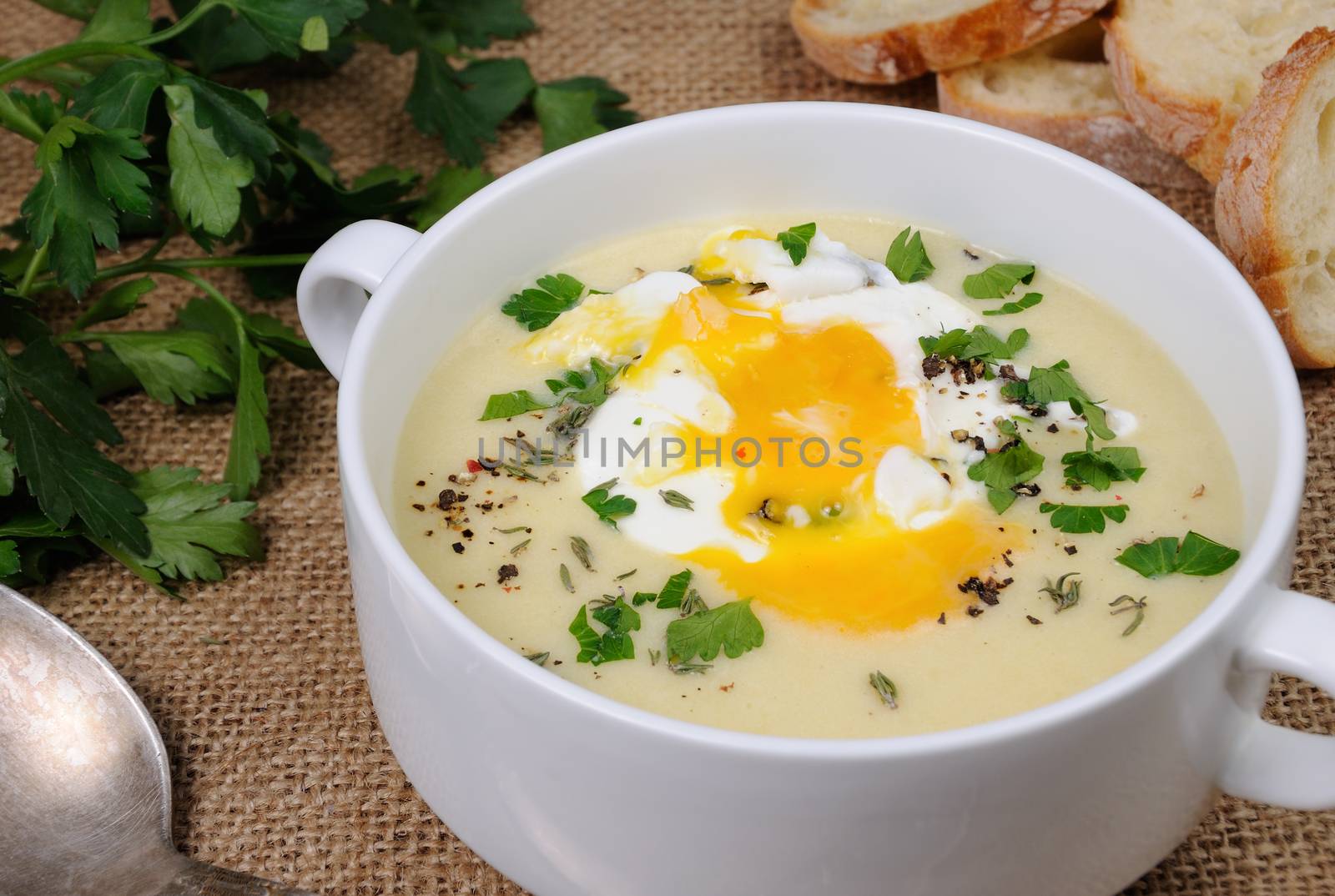 potato cream soup with bacon and poached eggs, herbs, spices