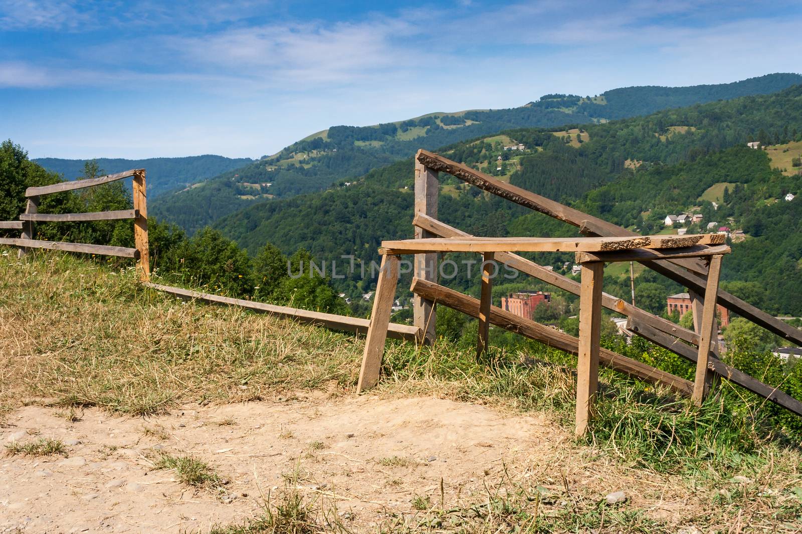 wooden stick fence in vilage in mountains with blue sky, green grass and path in good weather time