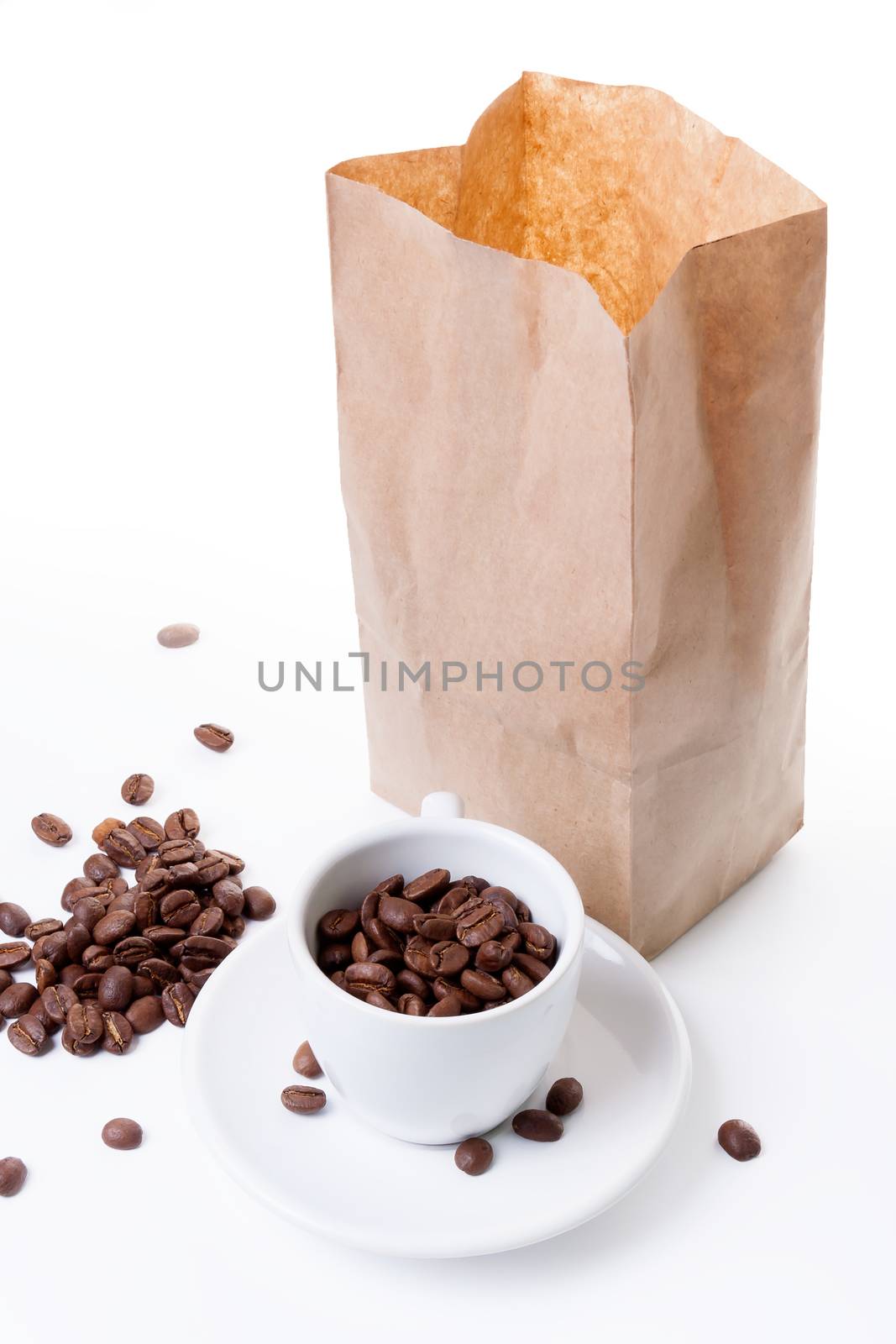 cup on a saucer and a paper bag filled with coffee on a white background