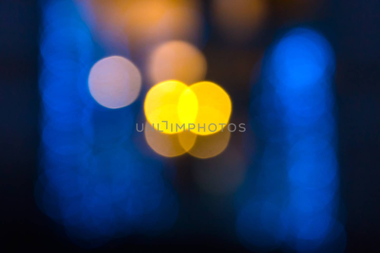 abstract evning blue background of blurred cool lights with warm yellow spot with bokeh effect