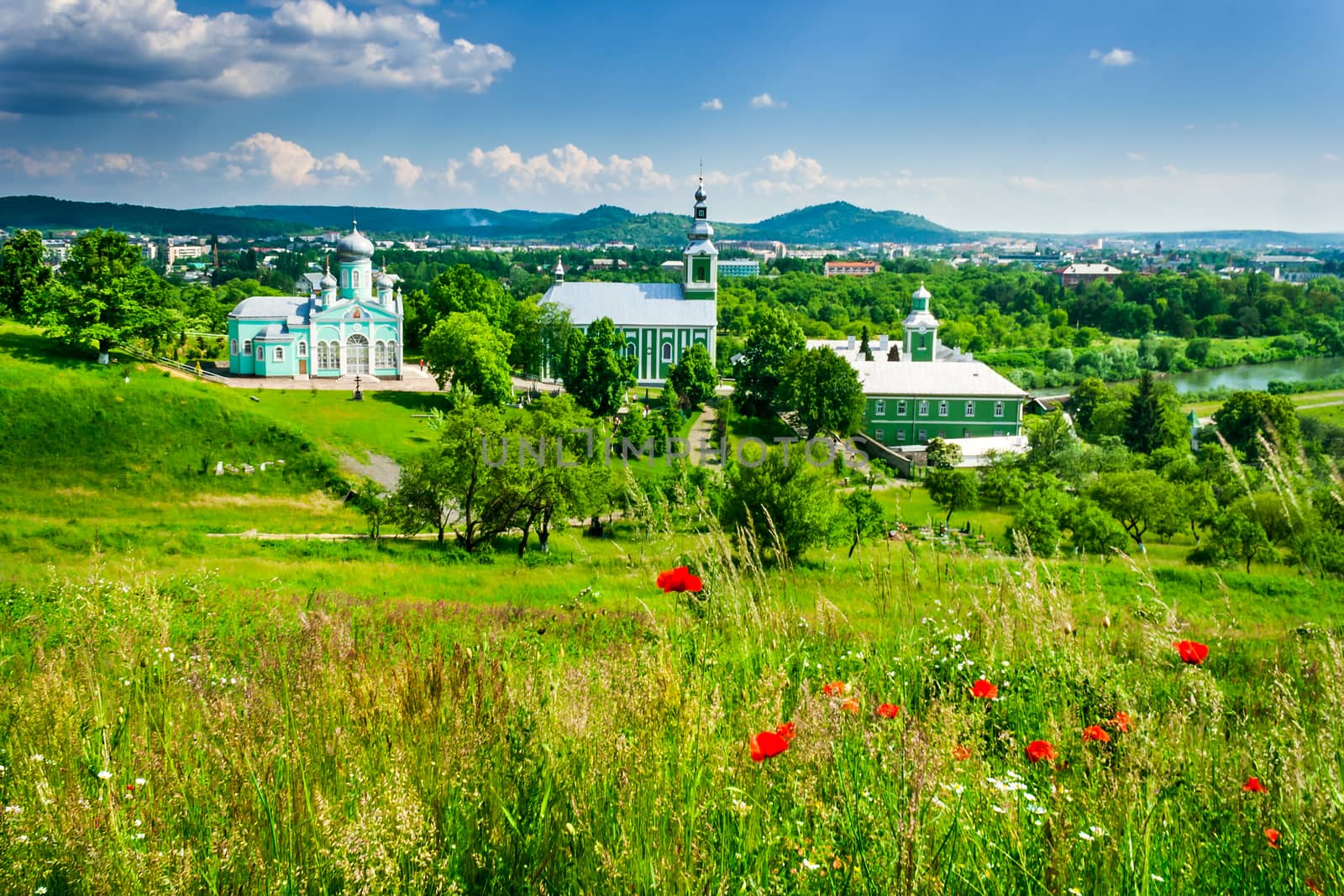 red poppy flowers in the grass and the monastery and church of green