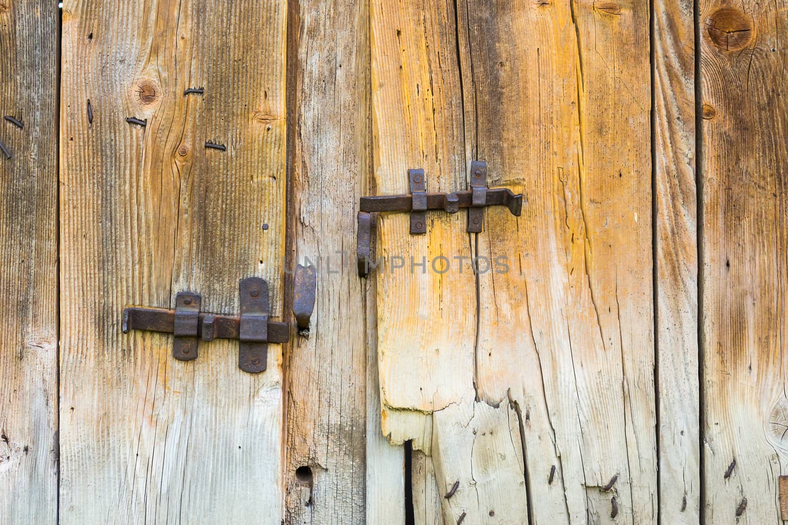 vintage wrought metal bars on the texture of broken wooden doors of dilapidated barn