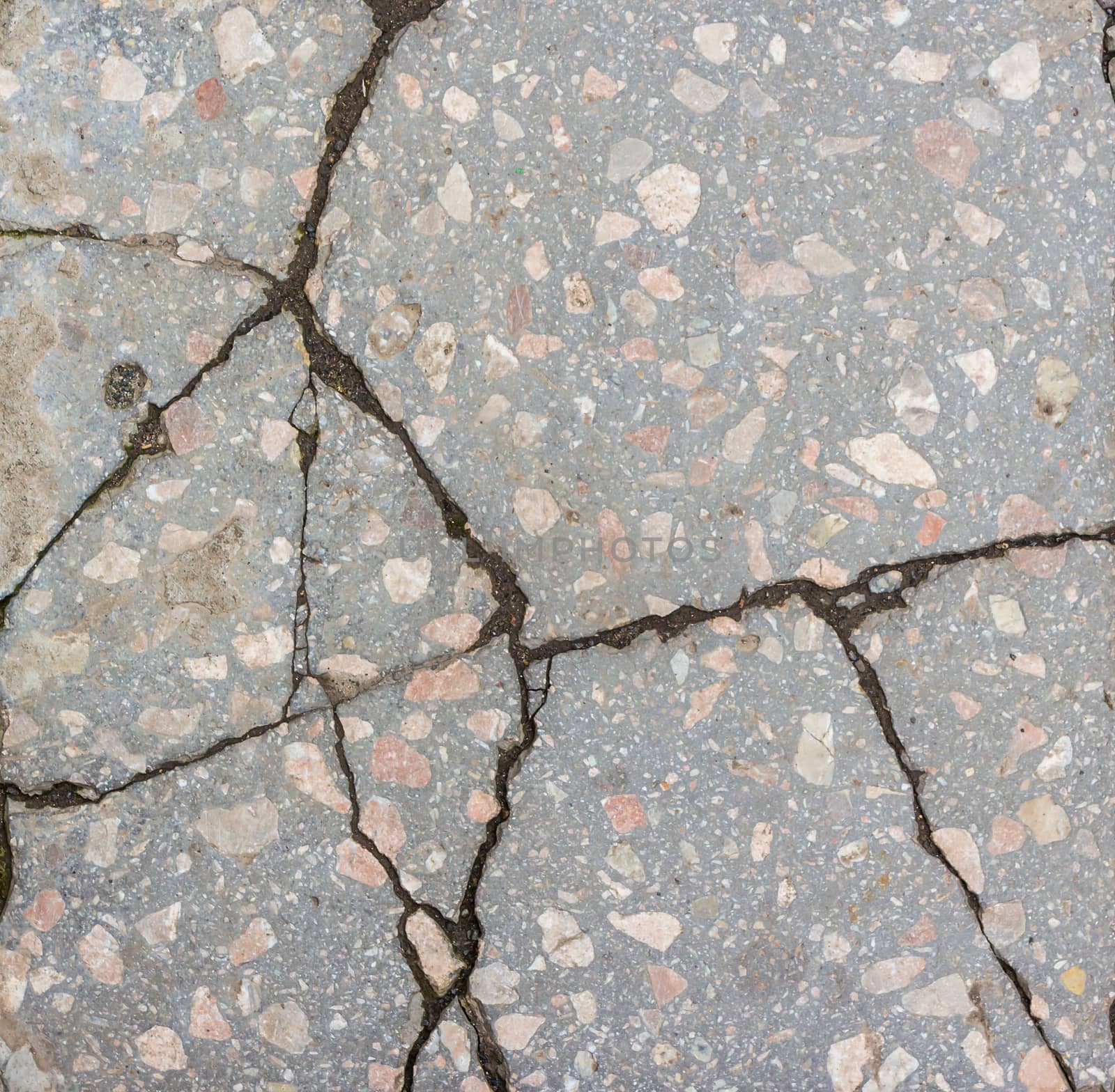a large number of deep cracks and small scratches in surface of the concrete with granite interspersed