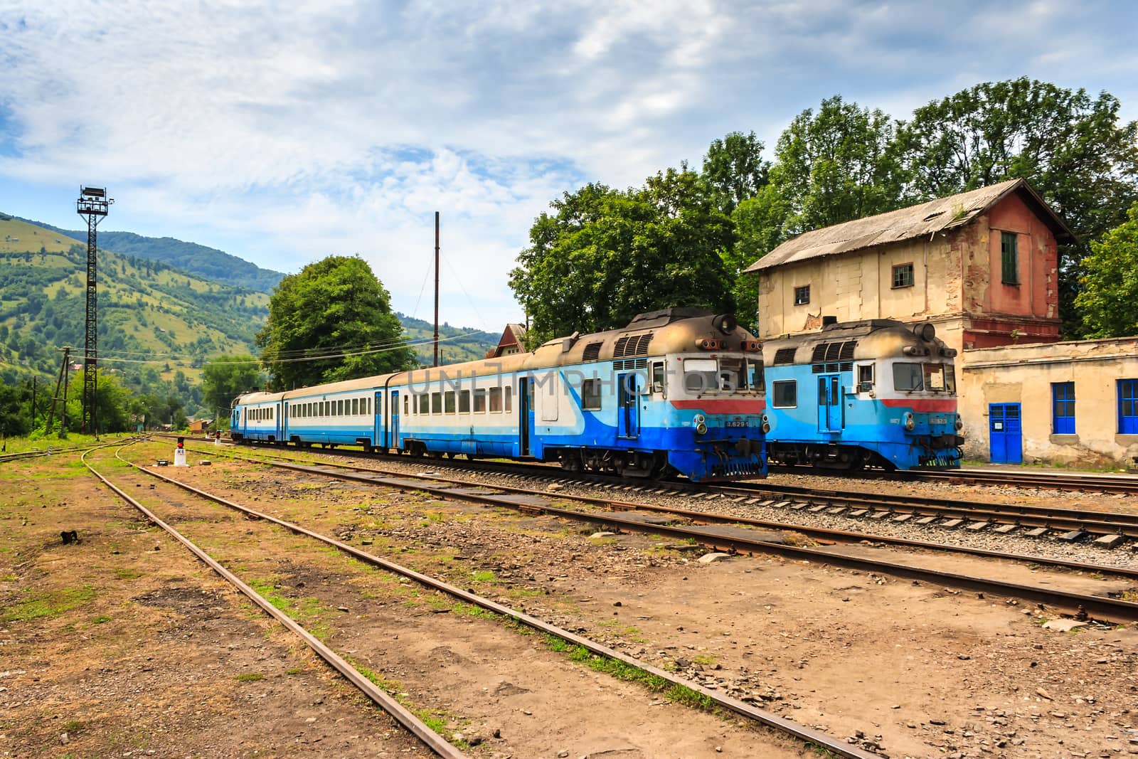 mountain railway station with two old blue train waiting passengers.
