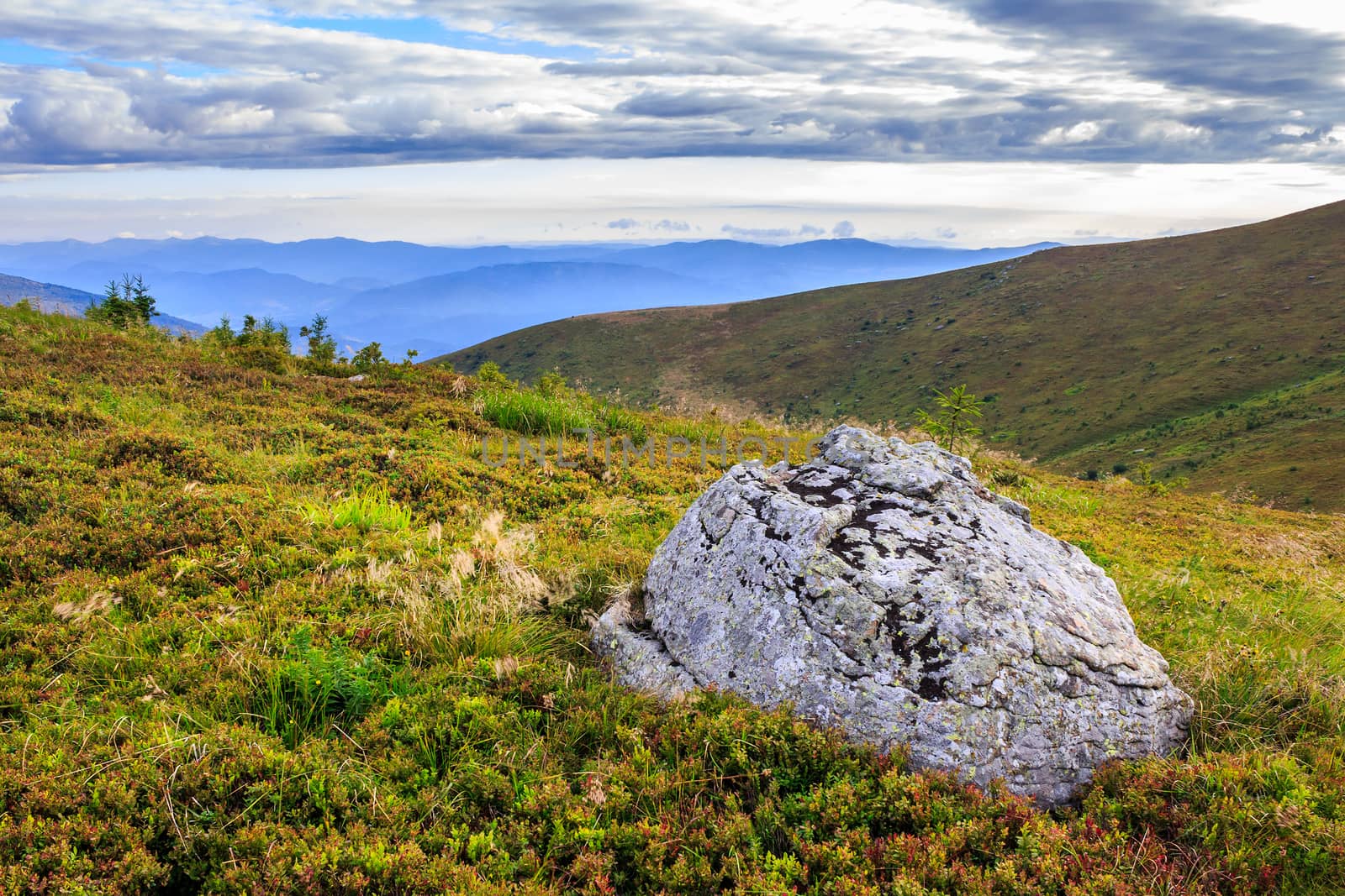 panorama of a mountain range and a large rock on the hillside