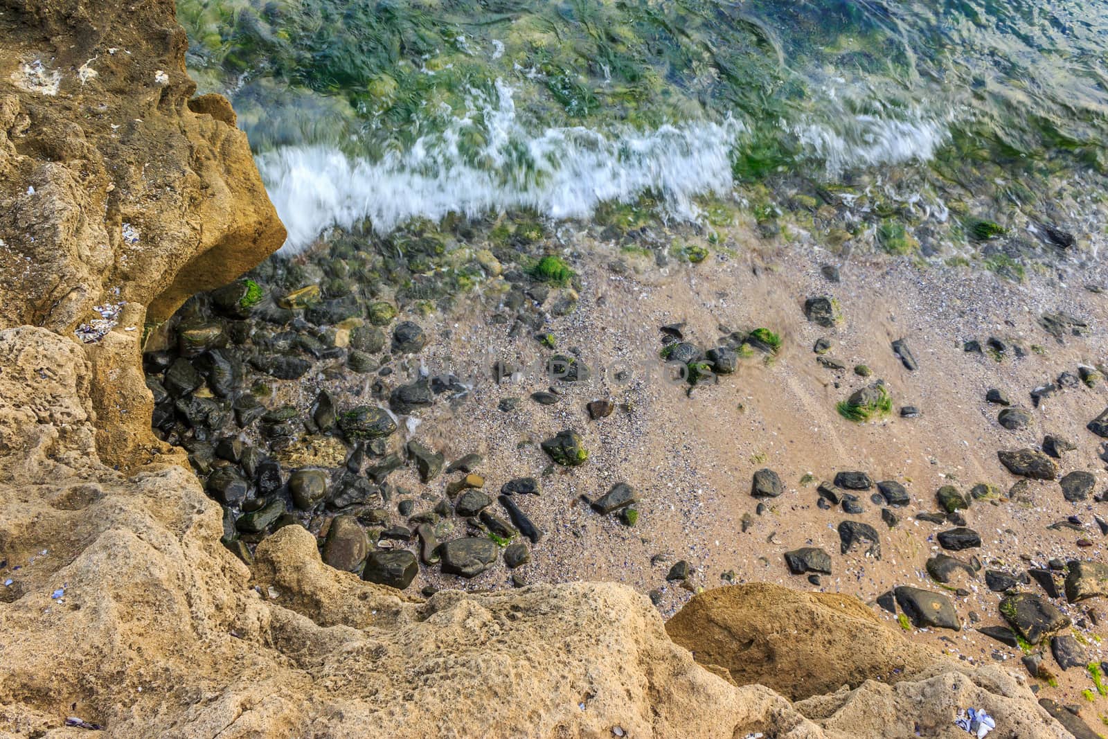 wave rolls onto the rocks on the sandy sea coast