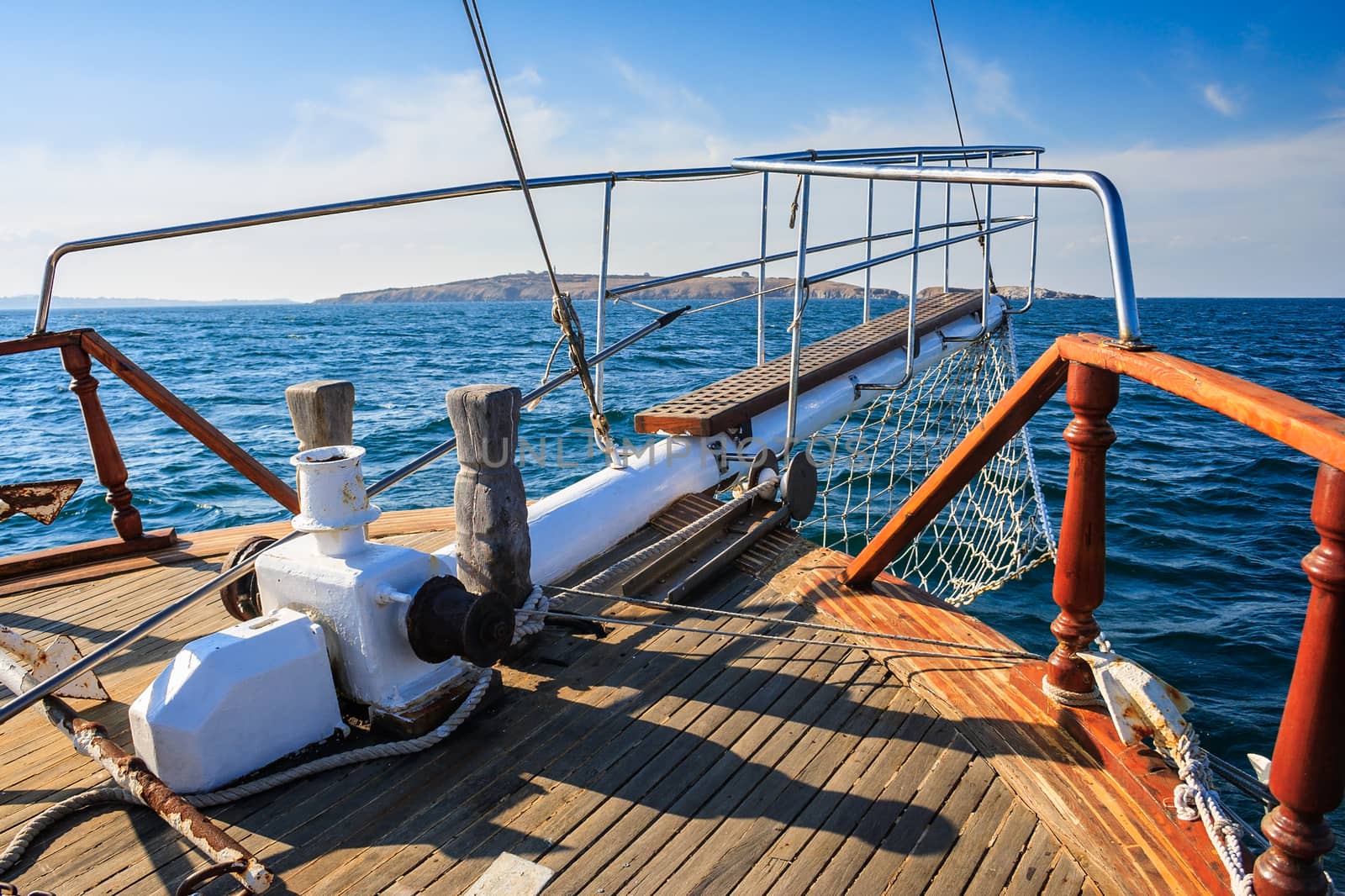 stem deck of a ship coming over the sea towards the island on a sunny day