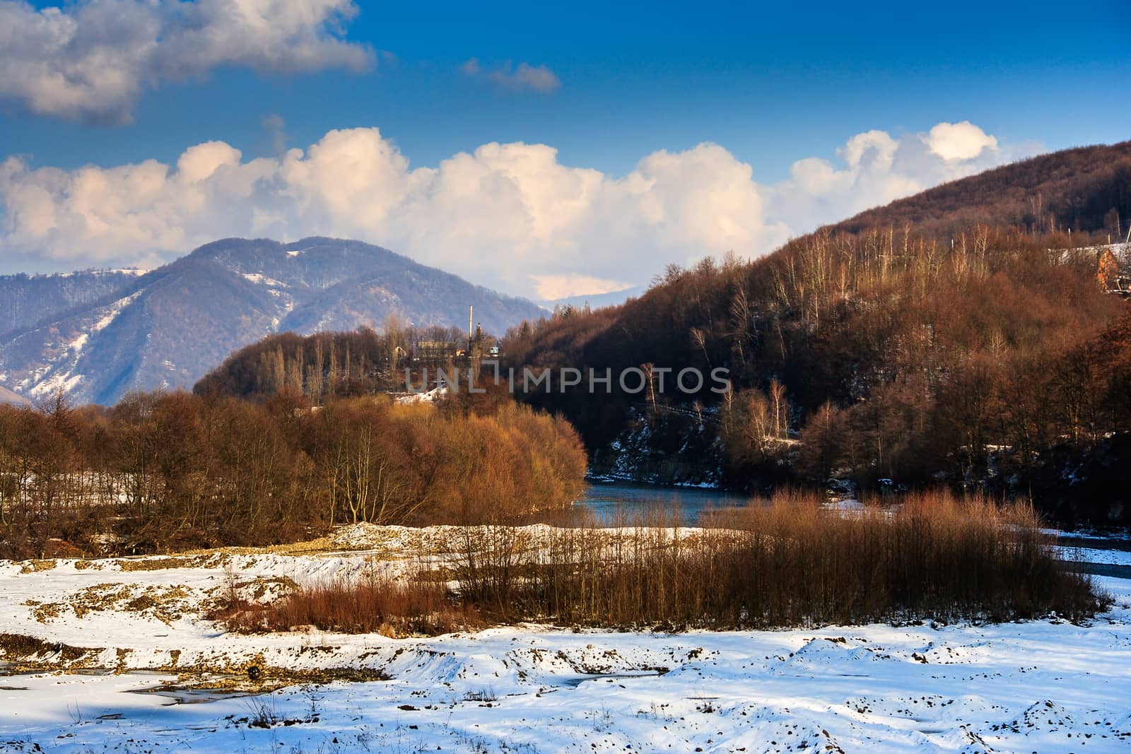 winter mountain landscape on clear day near the village and the river