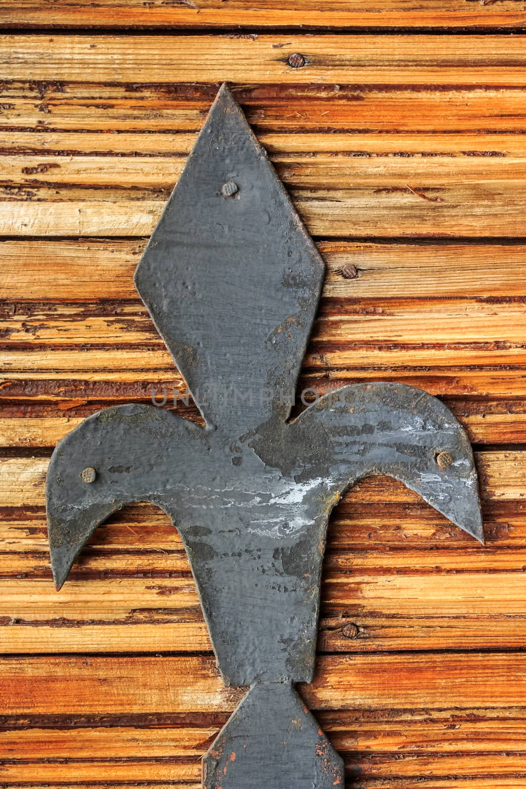 Painted black metal peak nailed to the surface of old painted wooden planks