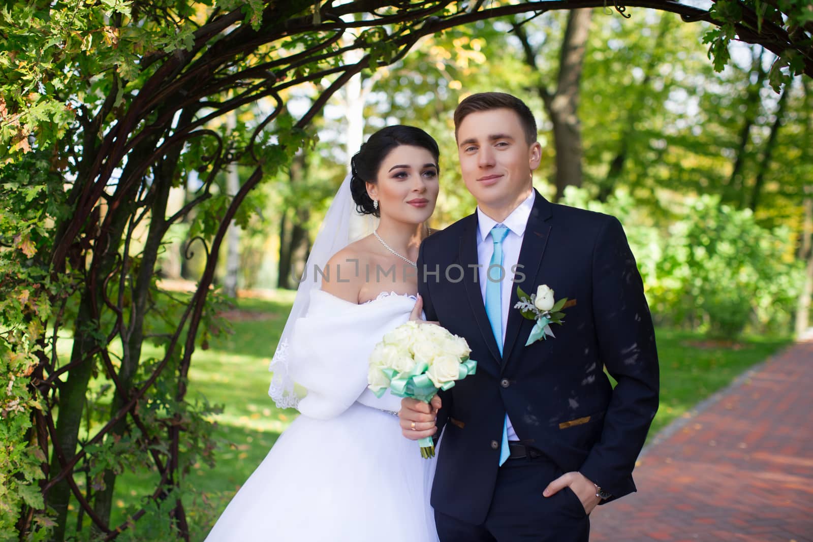 The bride tenderly embraced the groom standing under the green arch