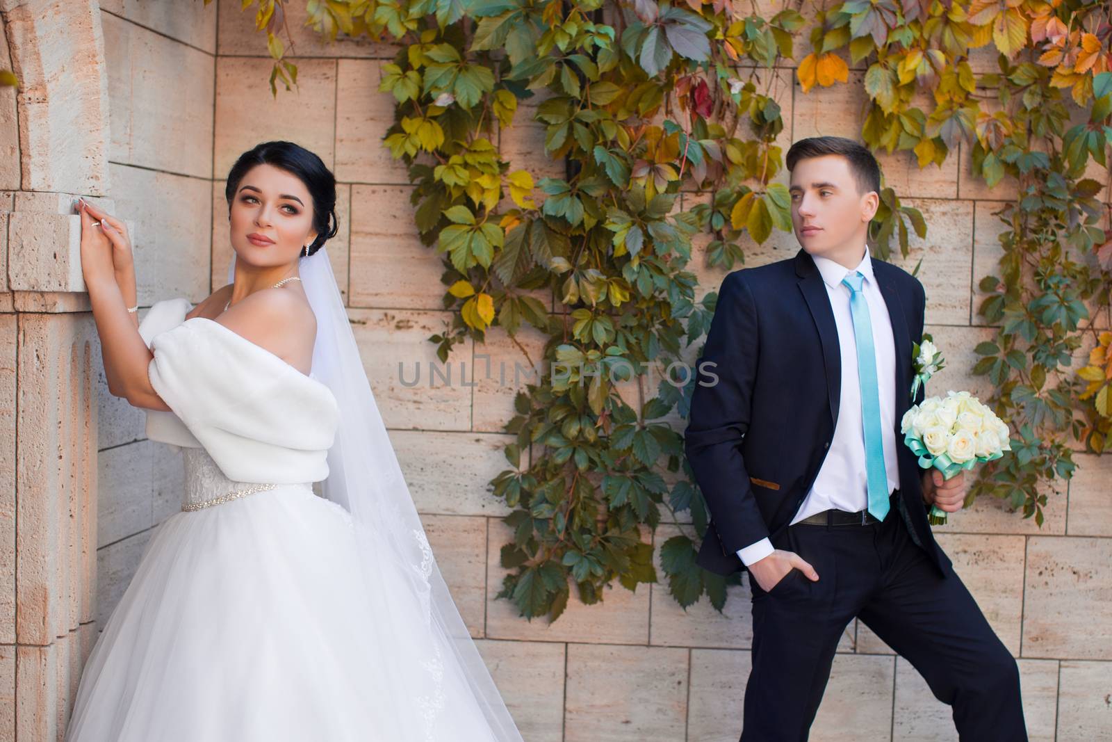 Stylish newlyweds posing on a photo shoot against the backdrop of a brick wall