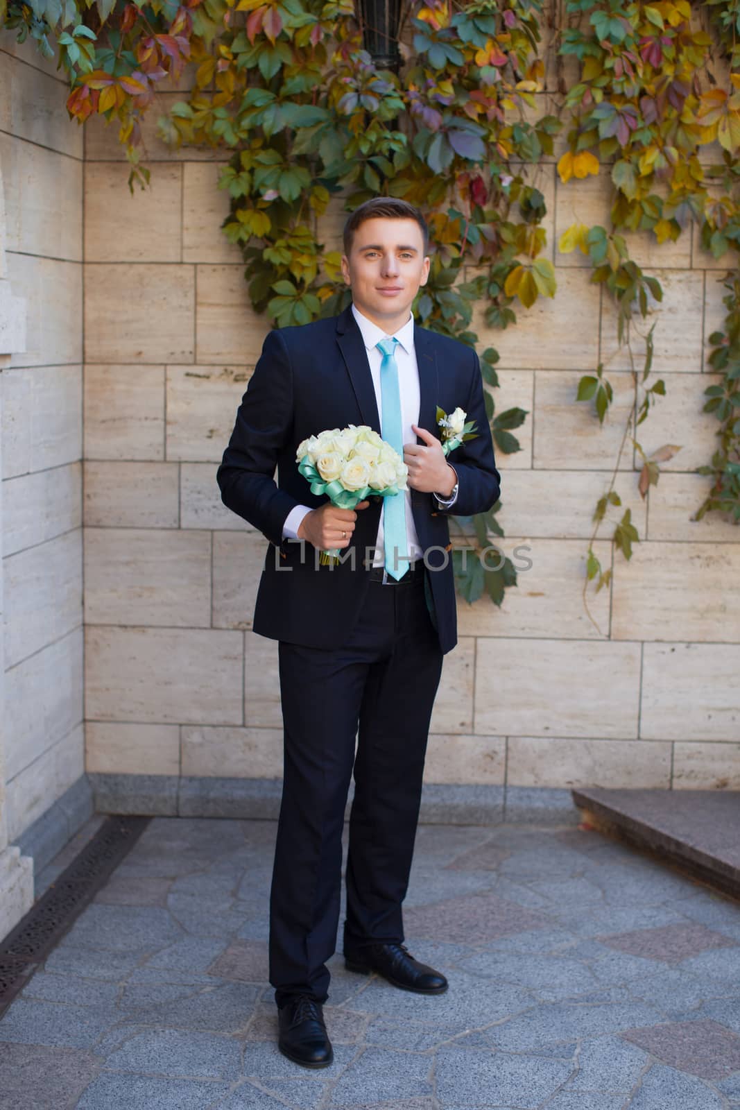 Groom in a stylish suit against a brick wall background by lanser314