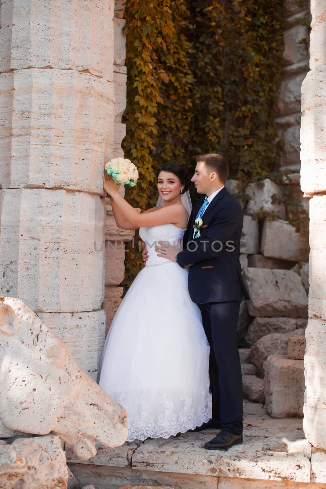 Happy newlyweds are standing by the column by lanser314