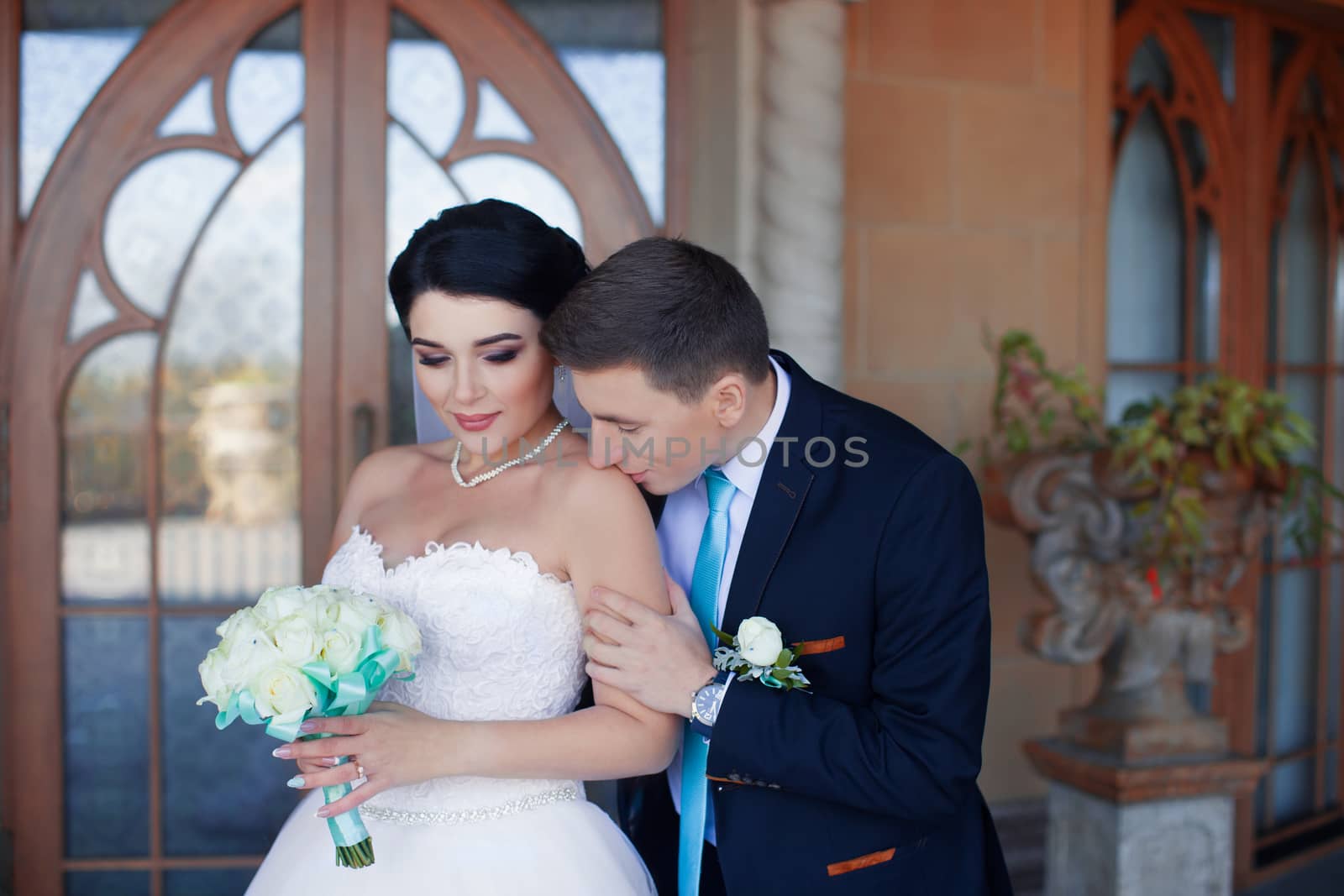 The groom tenderly kisses the bride's shoulder against the retro-door background