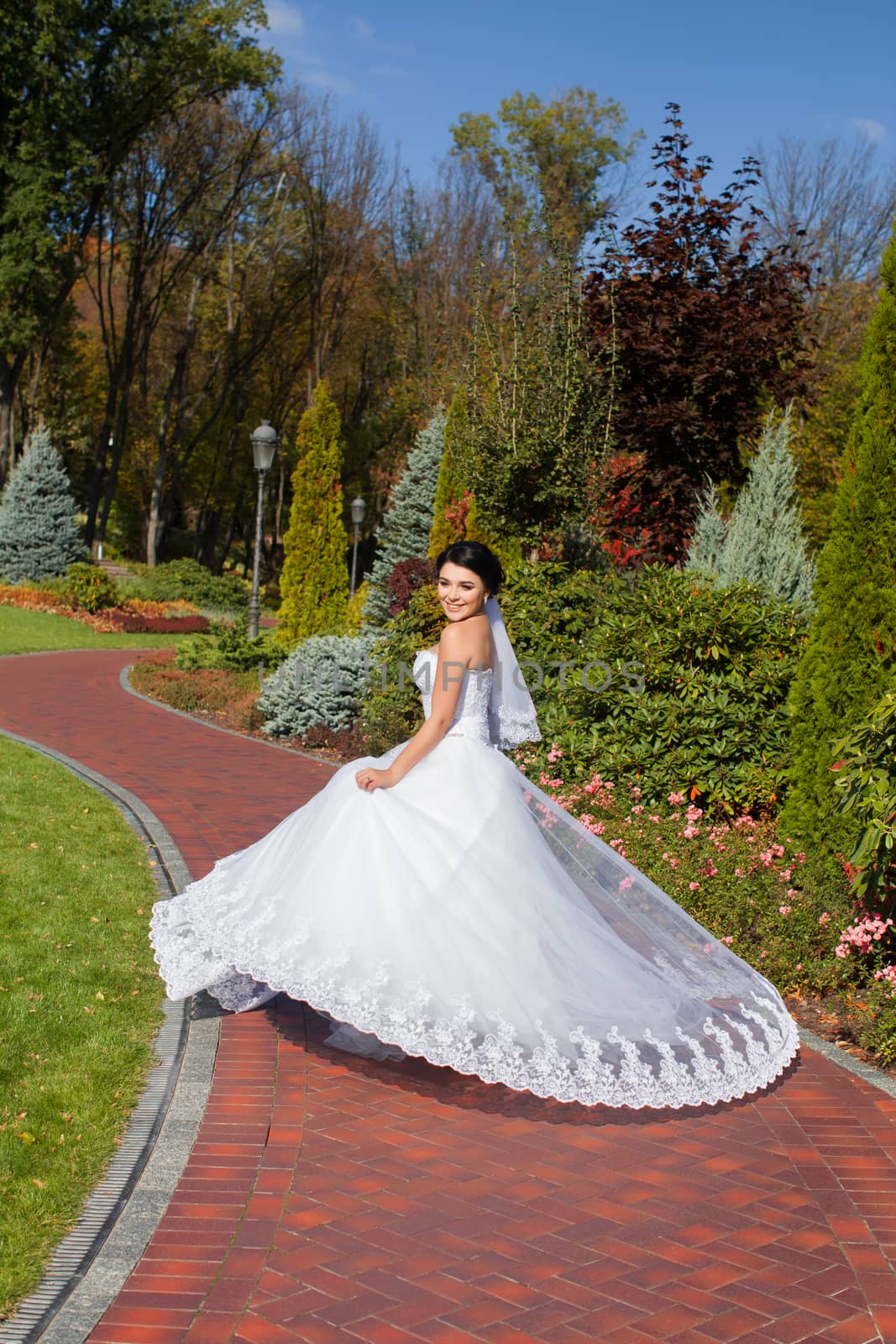 Bride on promenade in summer park posing on photo