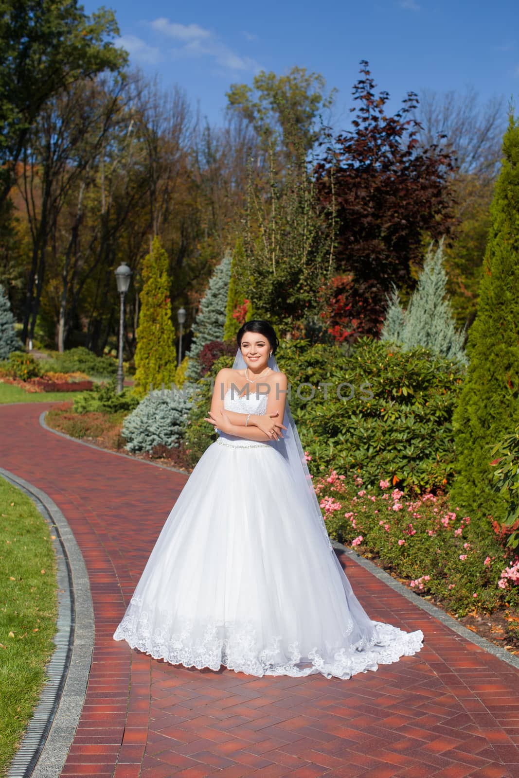 Bride on promenade in summer park posing on photo