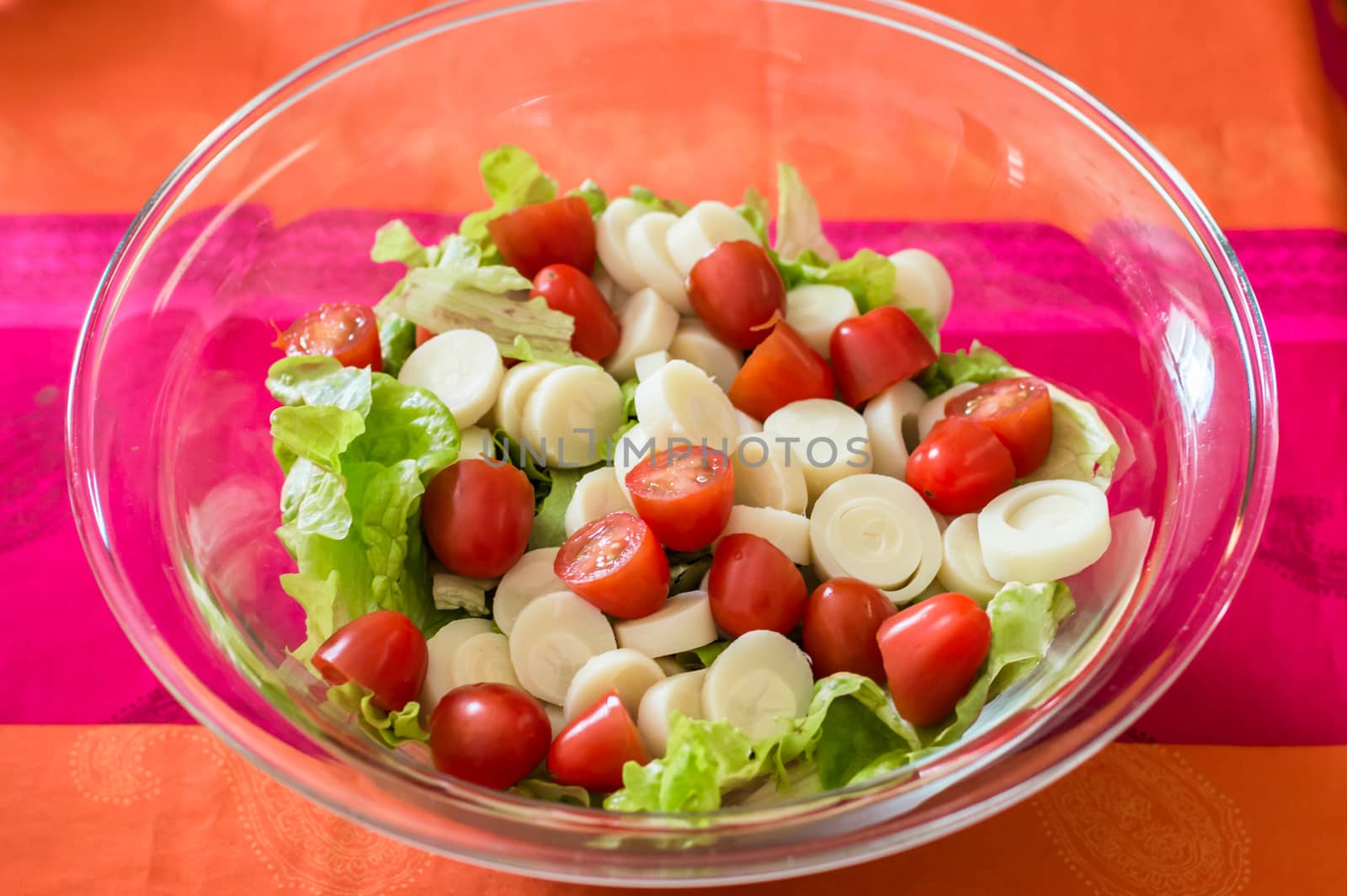 Close up salad with cherry tomatoes and lettuce in a glass bowl on the table