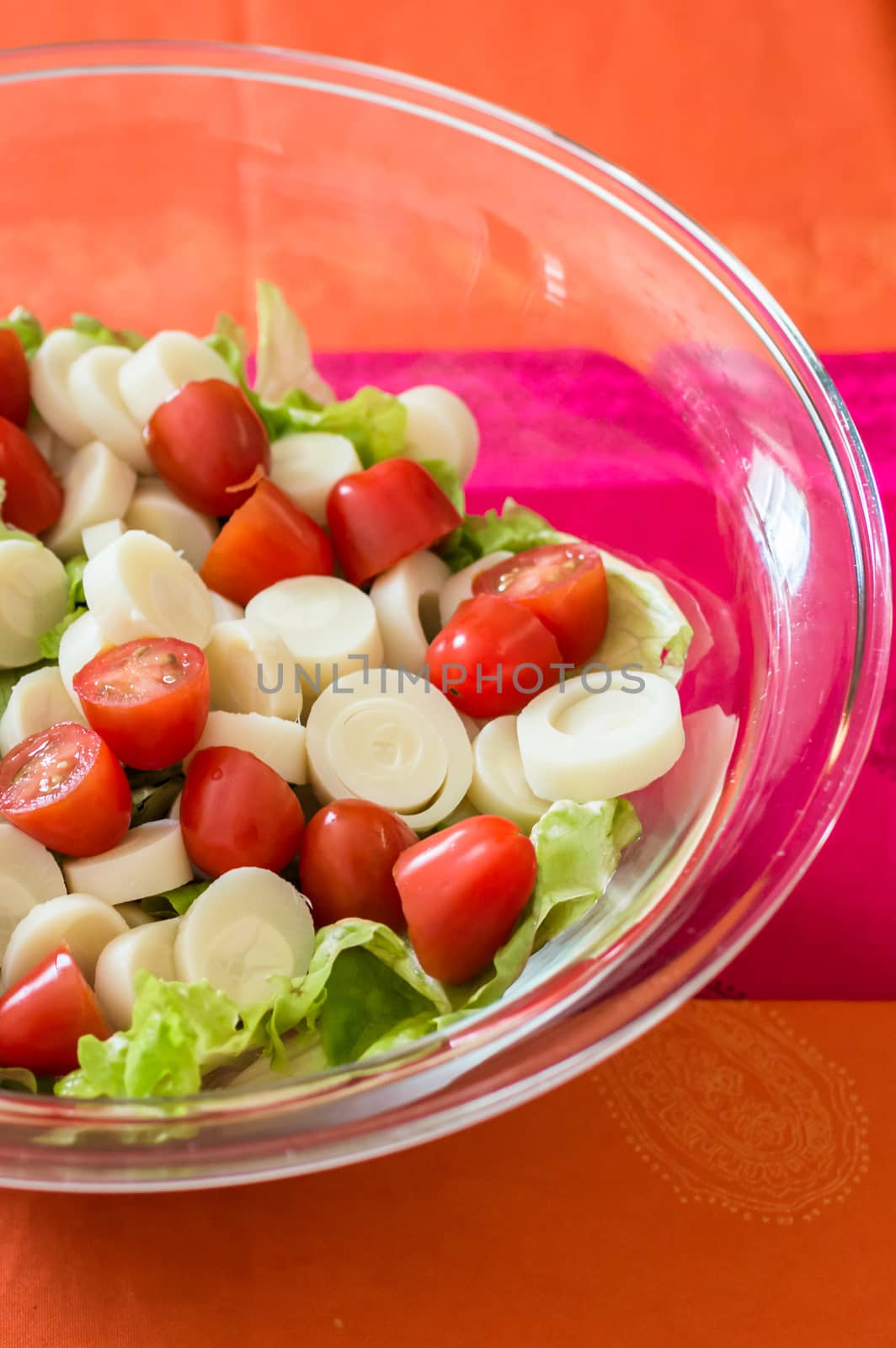Close up salad with cherry tomatoes and lettuce in a glass bowl on the table