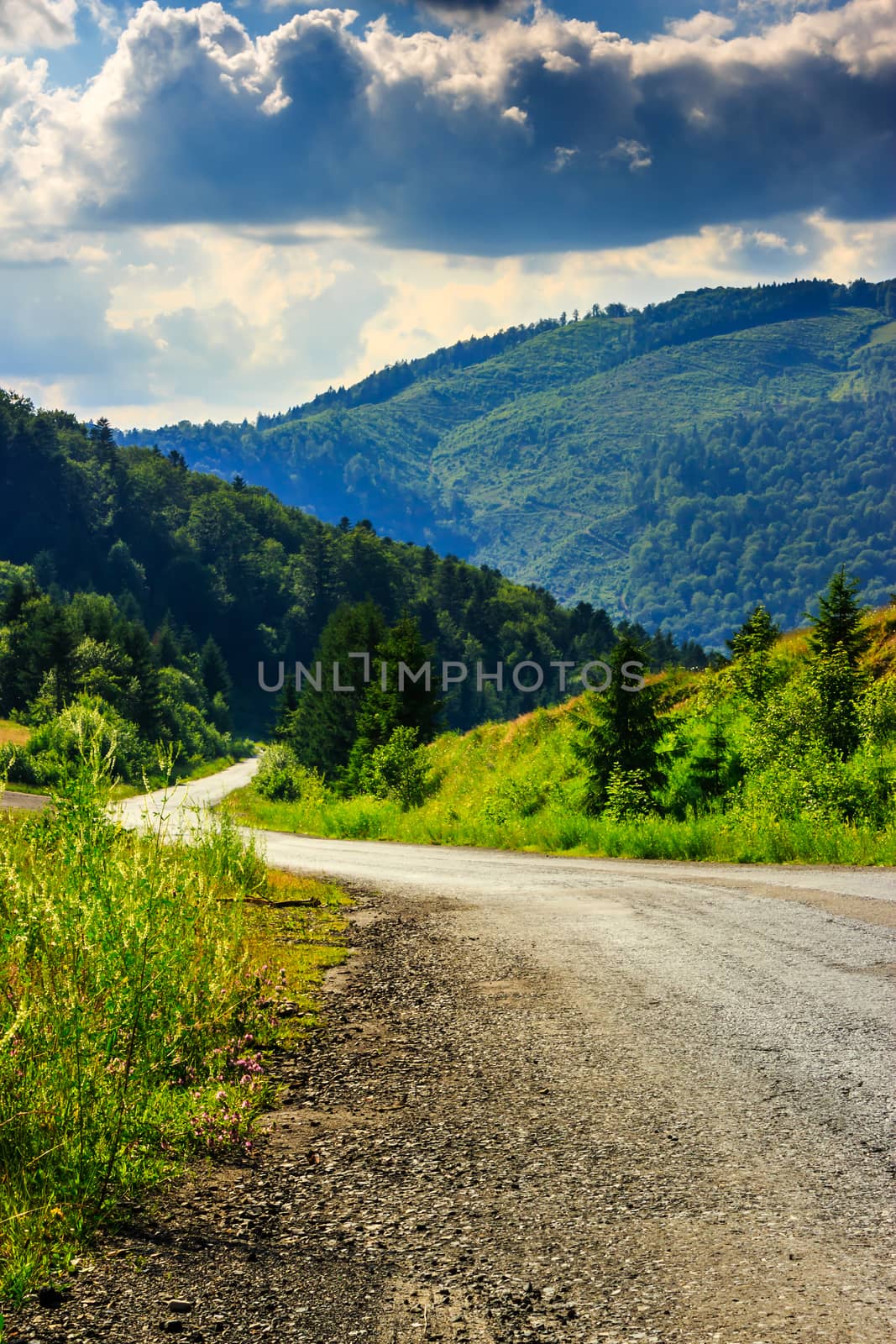 vertical winding road goes to mountains under a cloudy sky by Pellinni