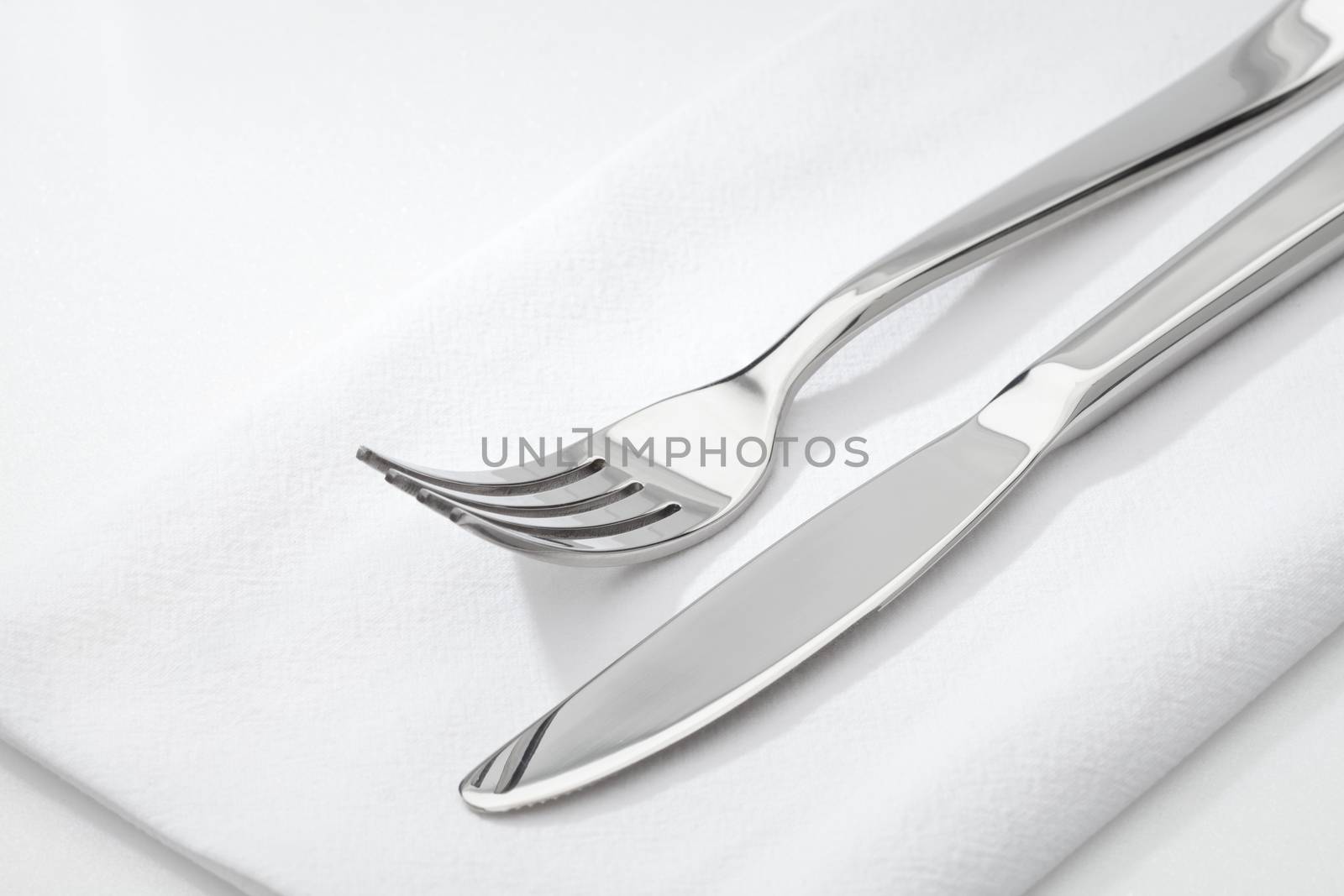 close up view of nice steel fork and knife on white napkin