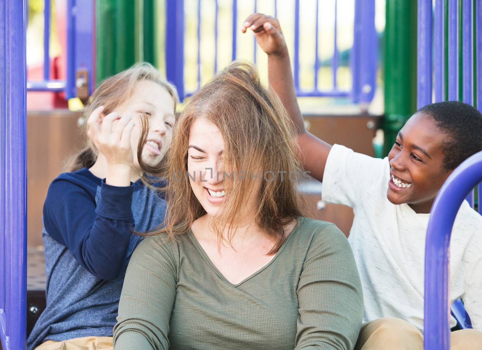 Silly children playing with hair of laughing woman