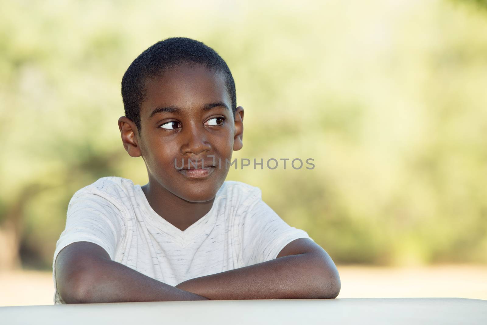 Grinning African child seated at table with copy space to his side
